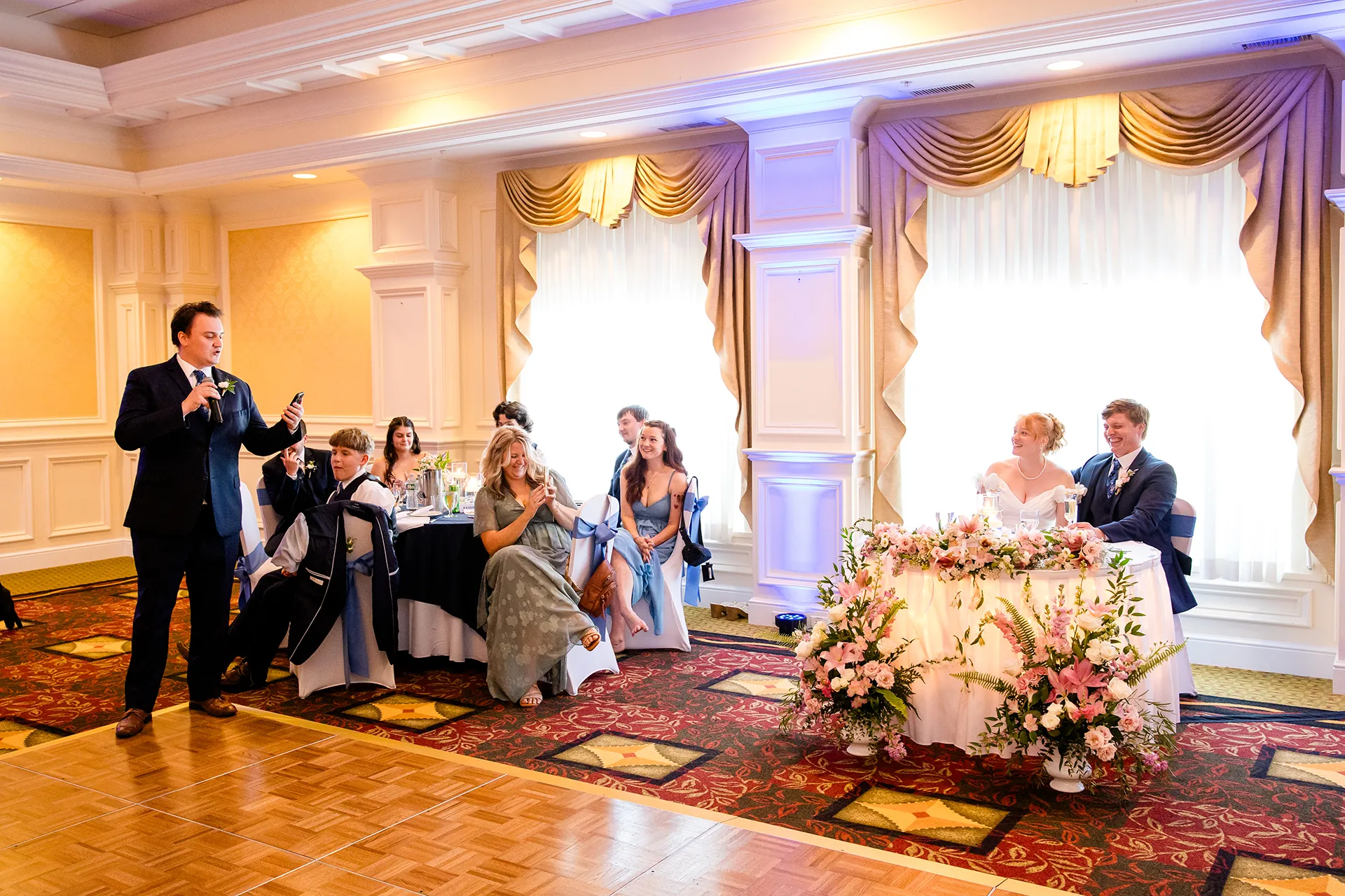 A bride and groom laugh as they listen to a groomsman give a toast during a wedding reception at Hilton Garden Inn in Bangor, Maine.