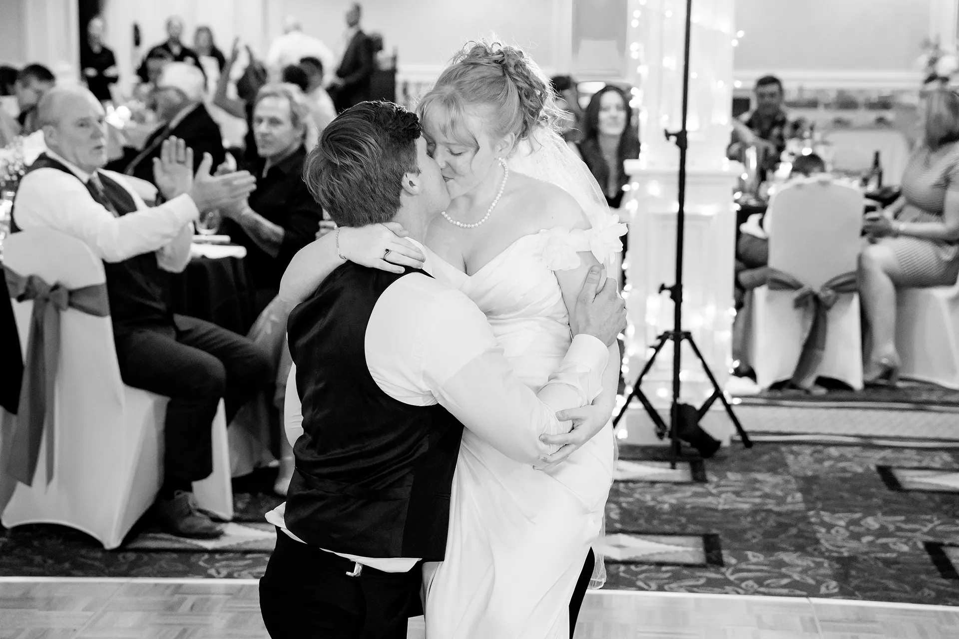 A brides sits on a groom's lap as they kiss during a wedding reception at Hilton Garden Inn in Bangor, Maine.