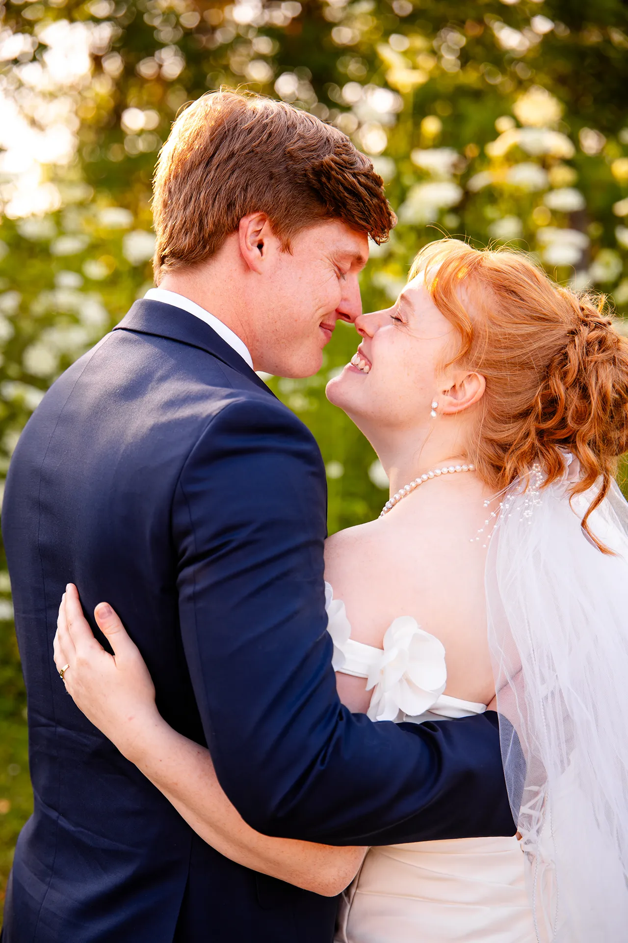 A bride and groom smile at each other while rubbing noses during wedding portraits at the Hilton Garden Inn in Bangor, Maine.