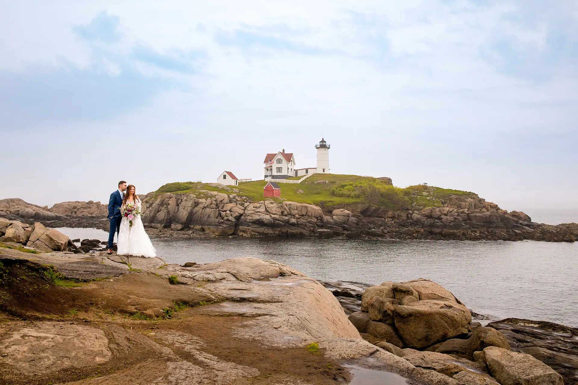 maine wedding photography bethany mike 20 A groom snuggles a bride during their wedding portraits at Nubble Lighthouse in York, Maine.
