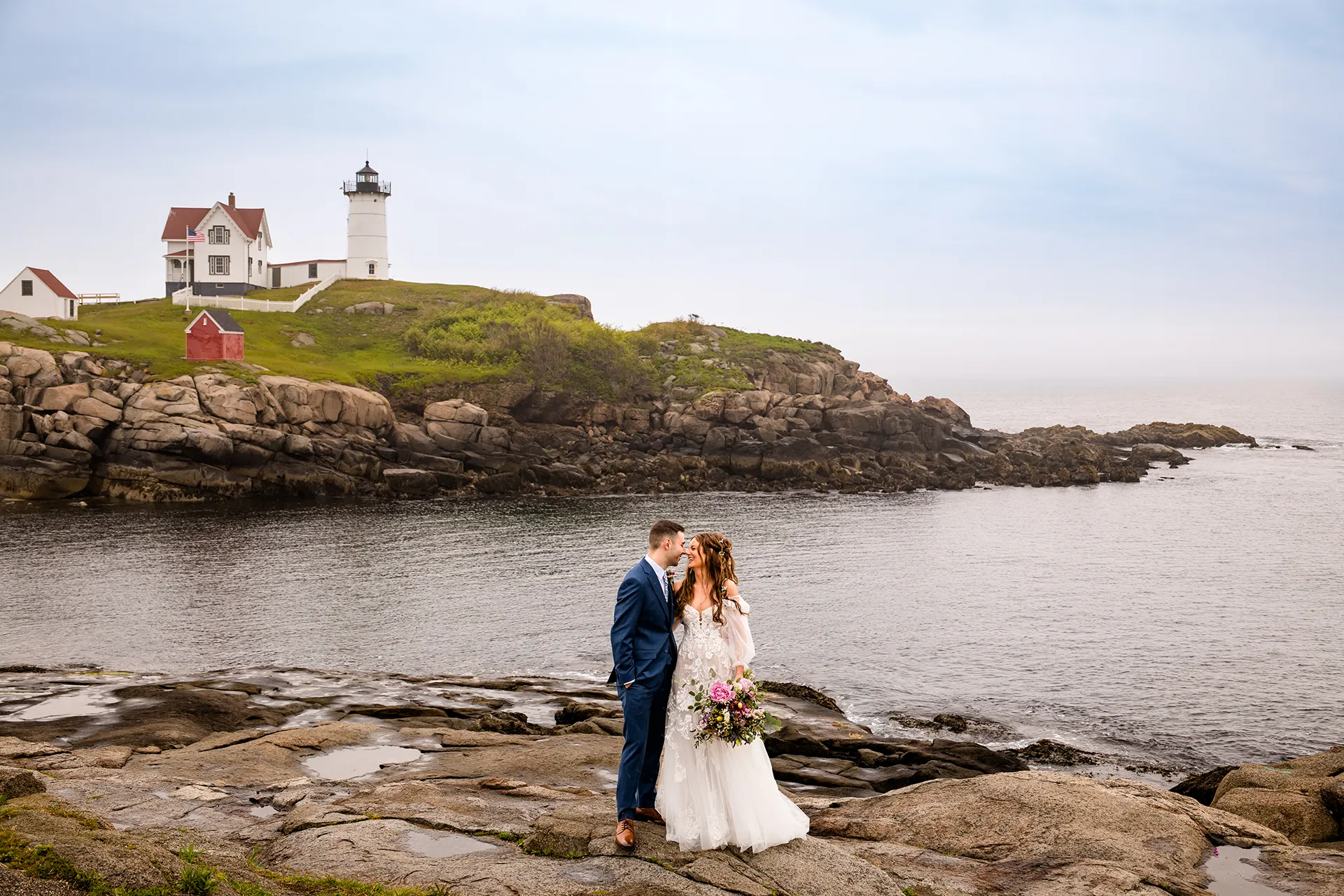 maine wedding photography bethany mike 23 A newly married couple pose in front of Nubble Lighthouse during their wedding portraits in York, Maine.