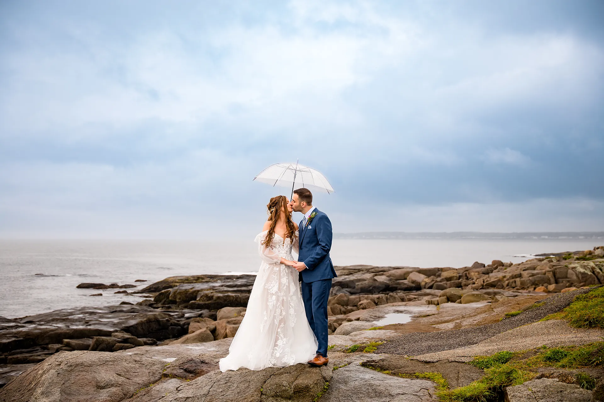maine wedding photography bethany mike 24 A bride and groom kiss under an umbrella during their wedding portraits at Nubble Lighthouse in York, Maine.