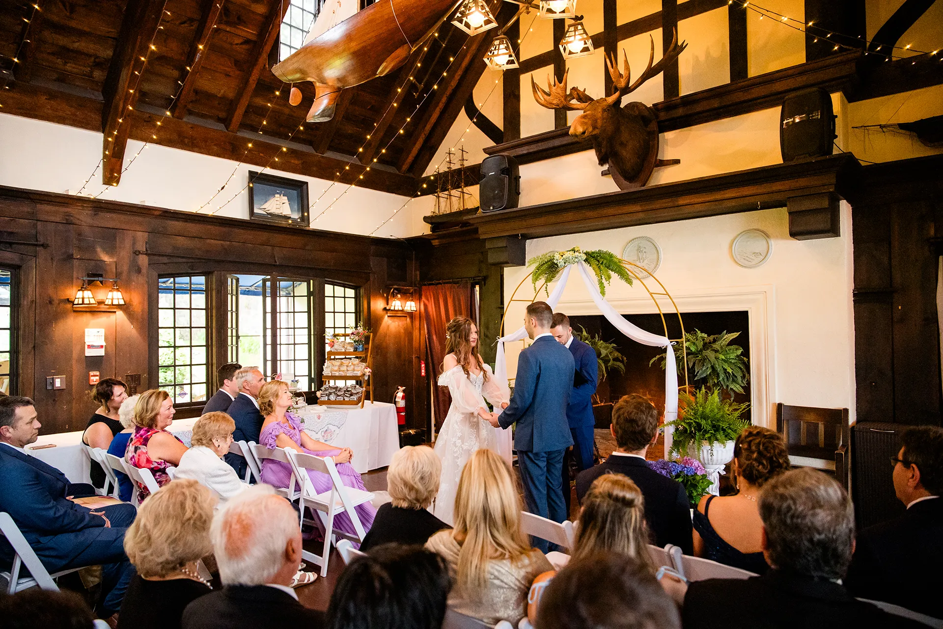 maine wedding photography bethany mike 31 A bride and groom hold hands as wedding guests watch them get married at York Harbor Reading Room in York, Maine.