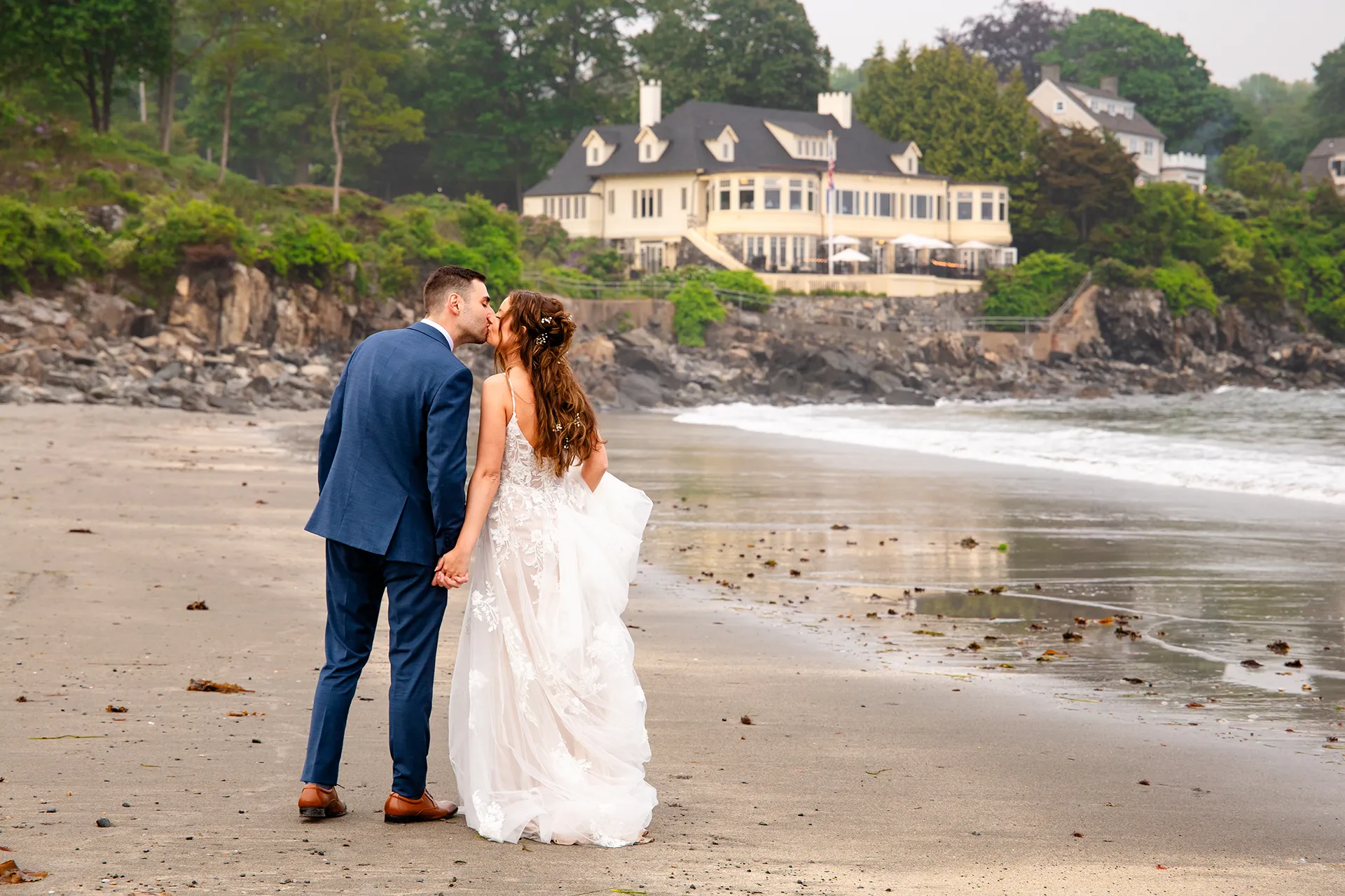 maine wedding photography bethany mike 42 A newly married couple kiss during wedding portraits on York Harbor Beach with the York Harbor Reading Room in the background.