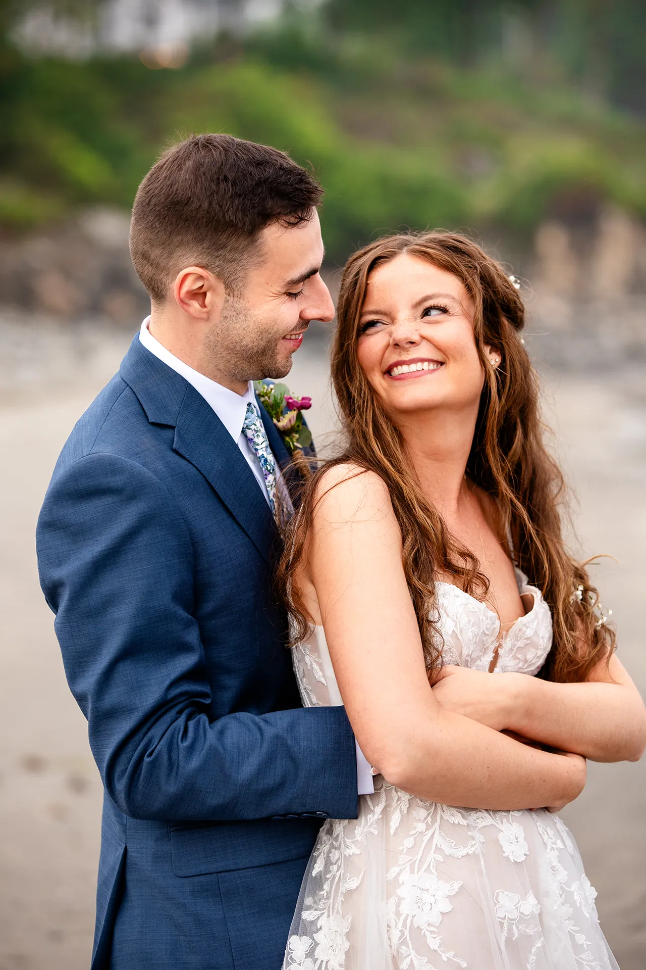 maine wedding photography bethany mike 48 A bride and groom smile at each other and snugg;e during wedding portraits on York Harbor Beach in York, Maine.