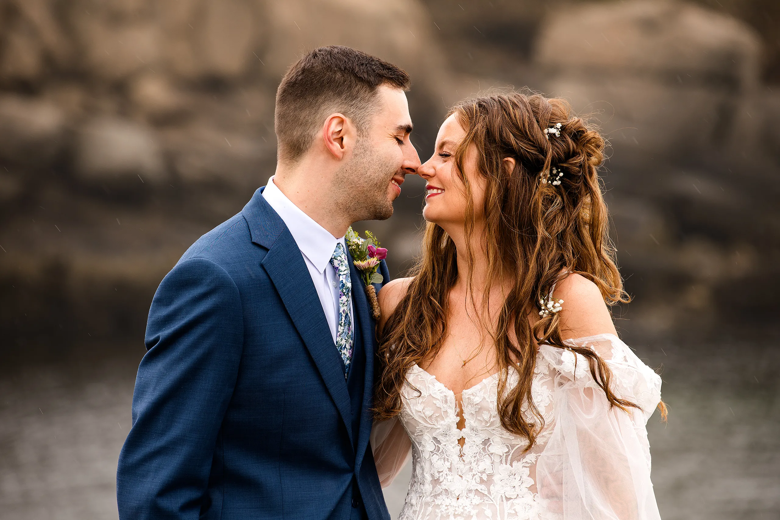 A bride and groom smile at each other during their wedding portraits Nubble Lighthouse in York, Maine.