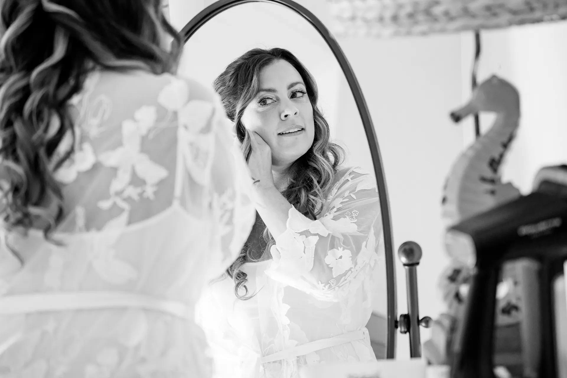 A bride looks in the mirror as she puts on her earrings as she get ready for a wedding at the Newagen Seaside Inn in Southport Maine.