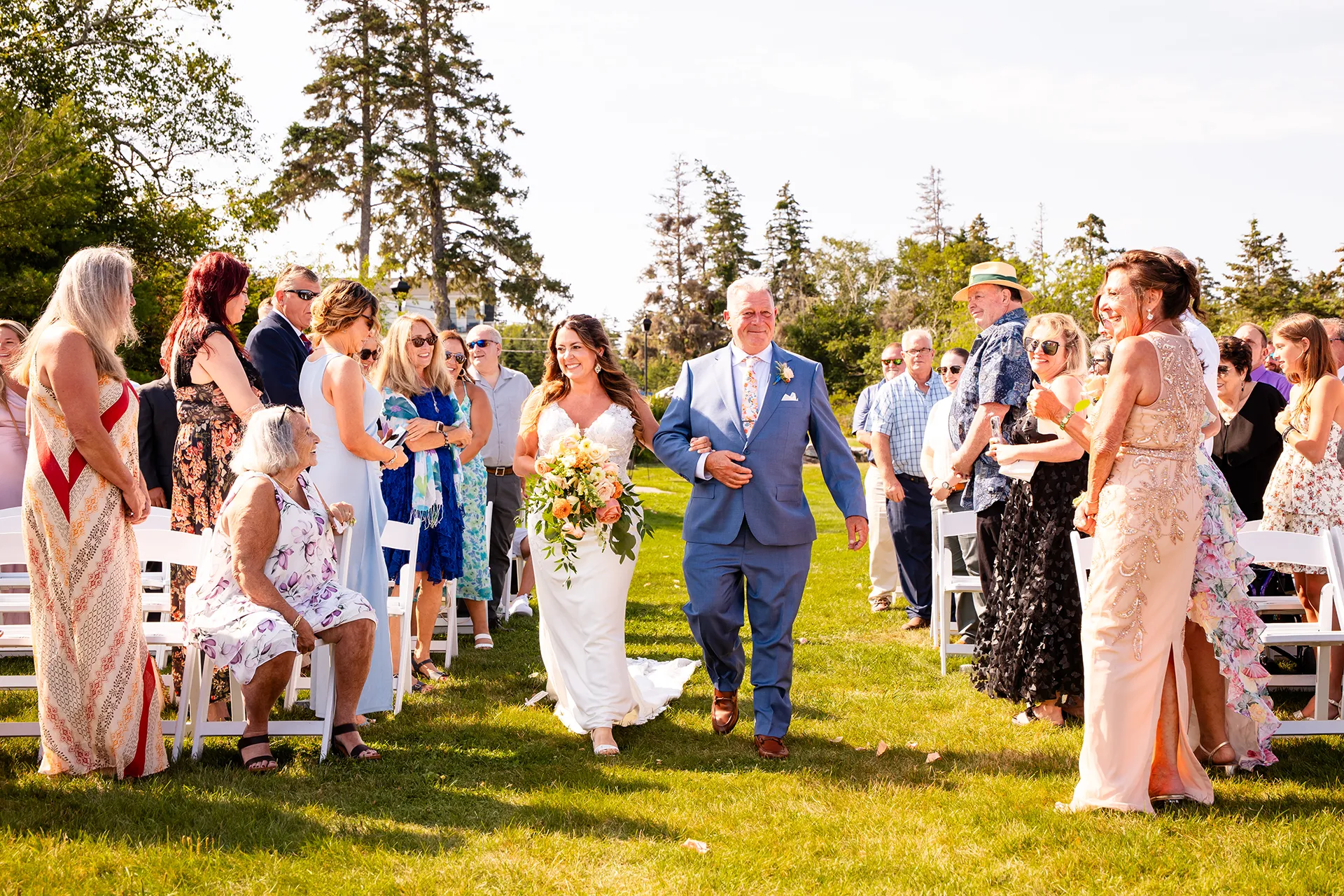A bride and dad smile as they walk down the aisle during a wedding ceremony at the Newagen Seaside Inn in Southport Maine.