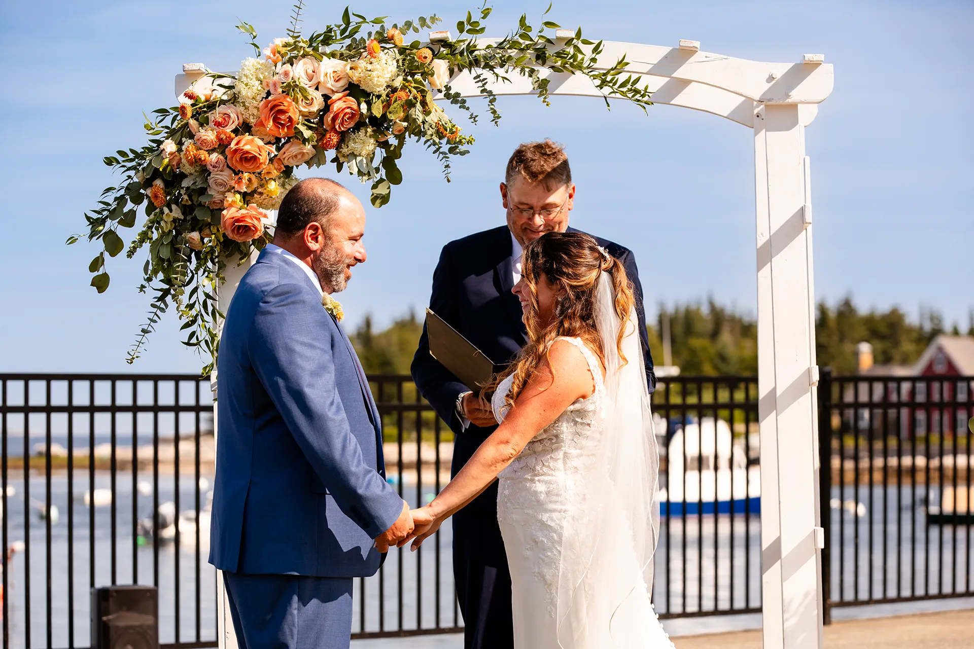 A bride and groom smile at each other and hold hands during a wedding ceremony at the Newagen Seaside Inn in Southport Maine.