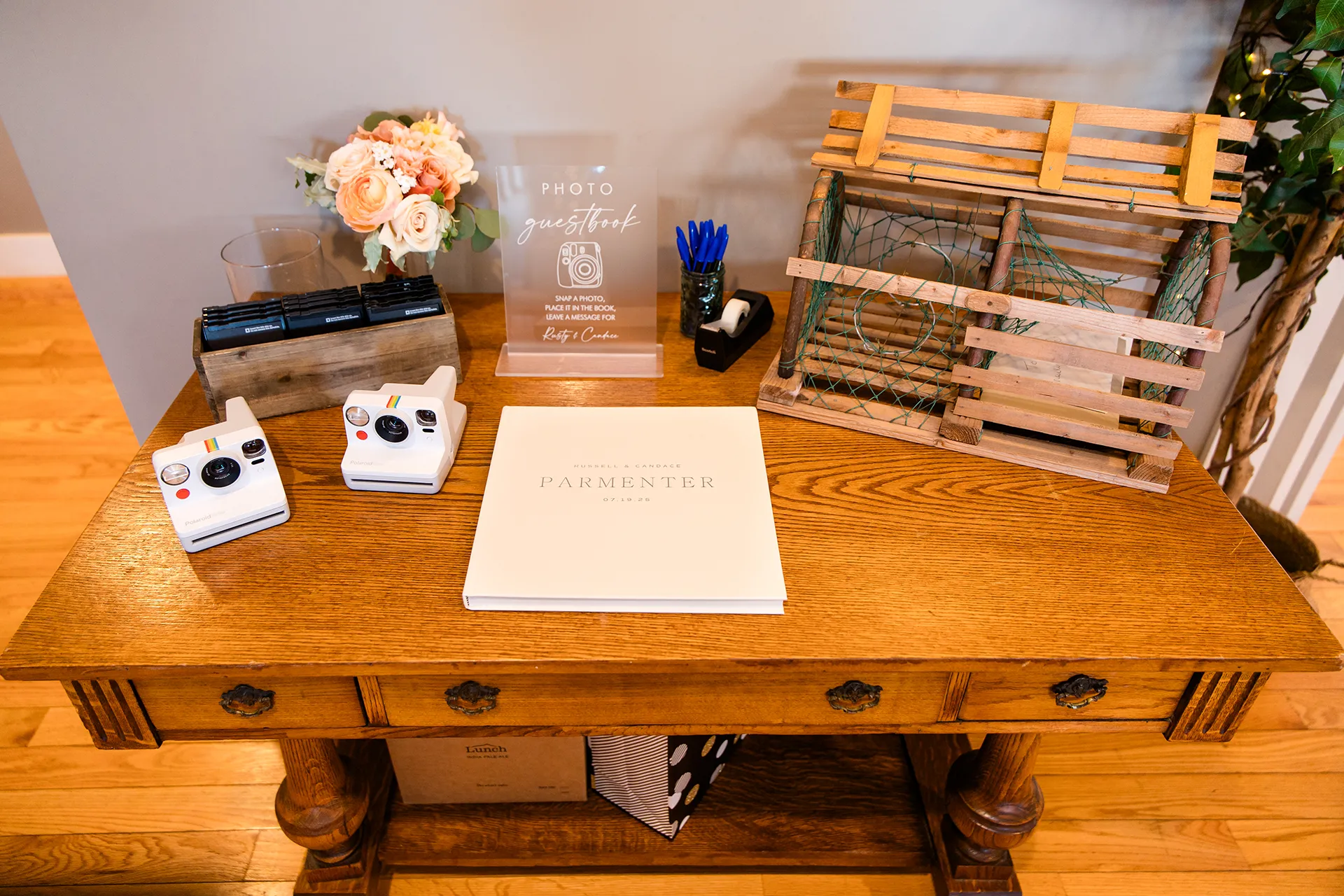 A wooden table with lobster trap, guests book and cameras for a wedding reception at the Newagen Seaside Inn in Southport Maine.