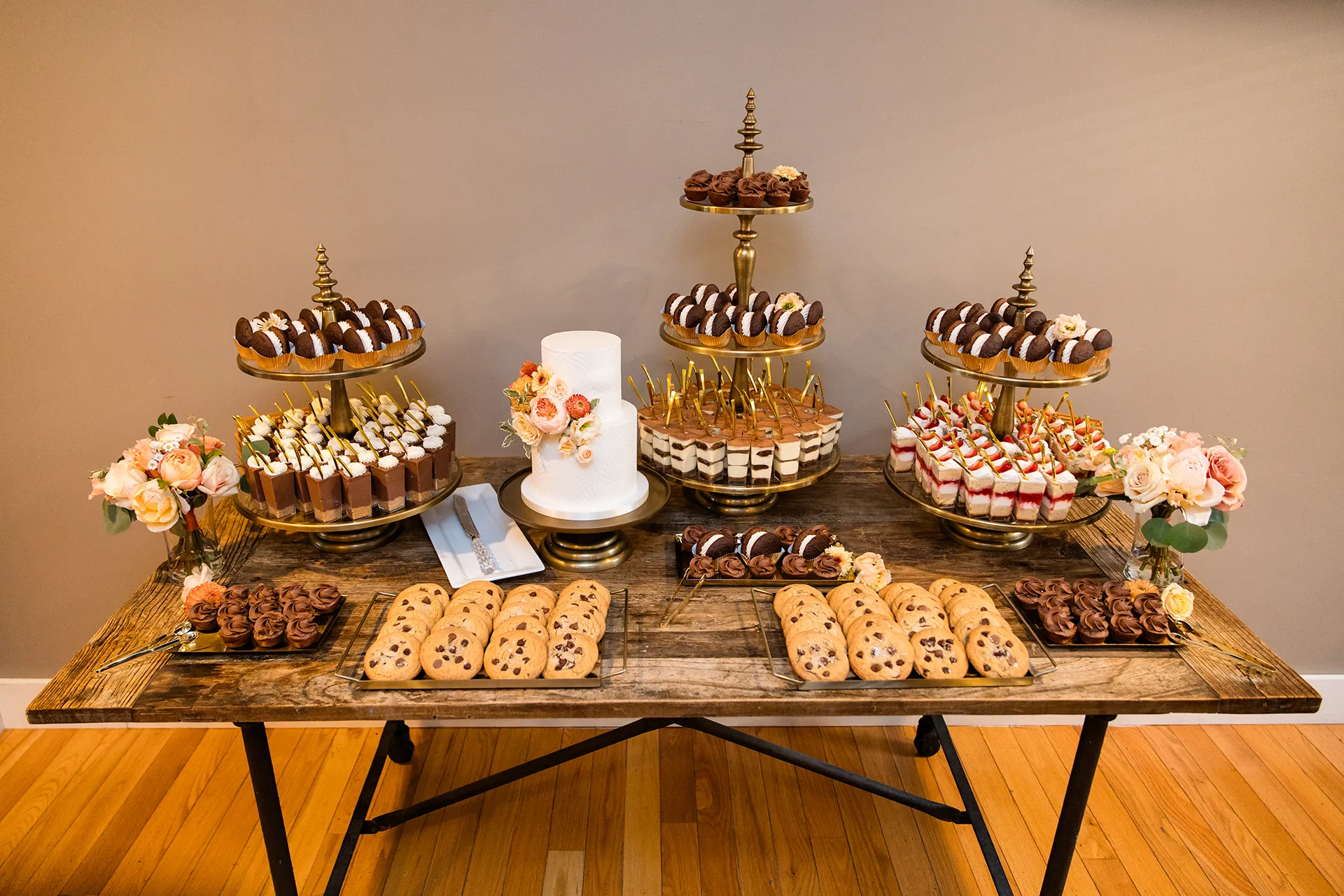 A wooden table with a wedding cake, cookies, and other assorted desserts for a wedding reception at the Newagen Seaside Inn in Southport Maine.