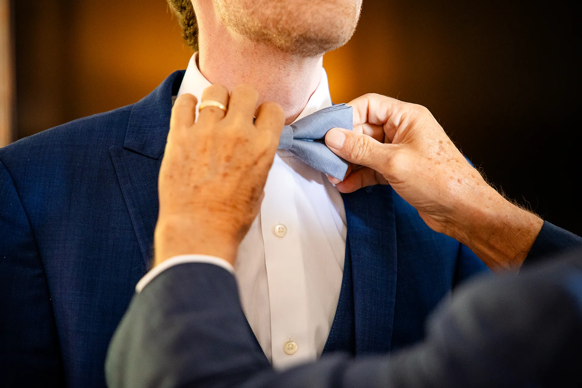 maine wedding photography caroline max 02 A closeup of a blue bowtie being adjusted for a wedding at the Bar Harbor Inn and Spa in Bar Harbor, Maine.