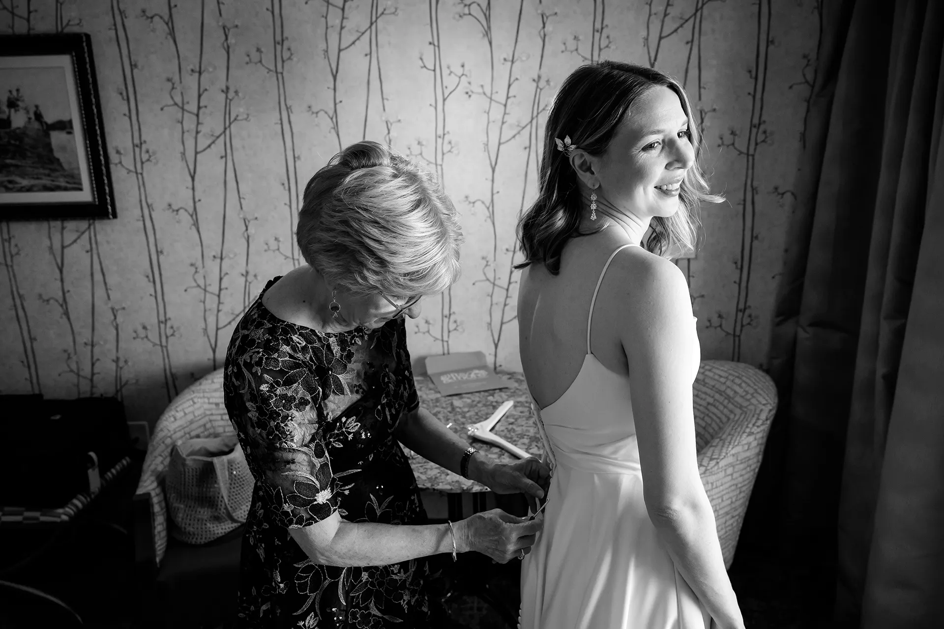 maine wedding photography caroline max 03 A mom button's up a bride's dress as she gets ready for a wedding at the Bar Harbor Inn and Spa in Bar Harbor, Maine.