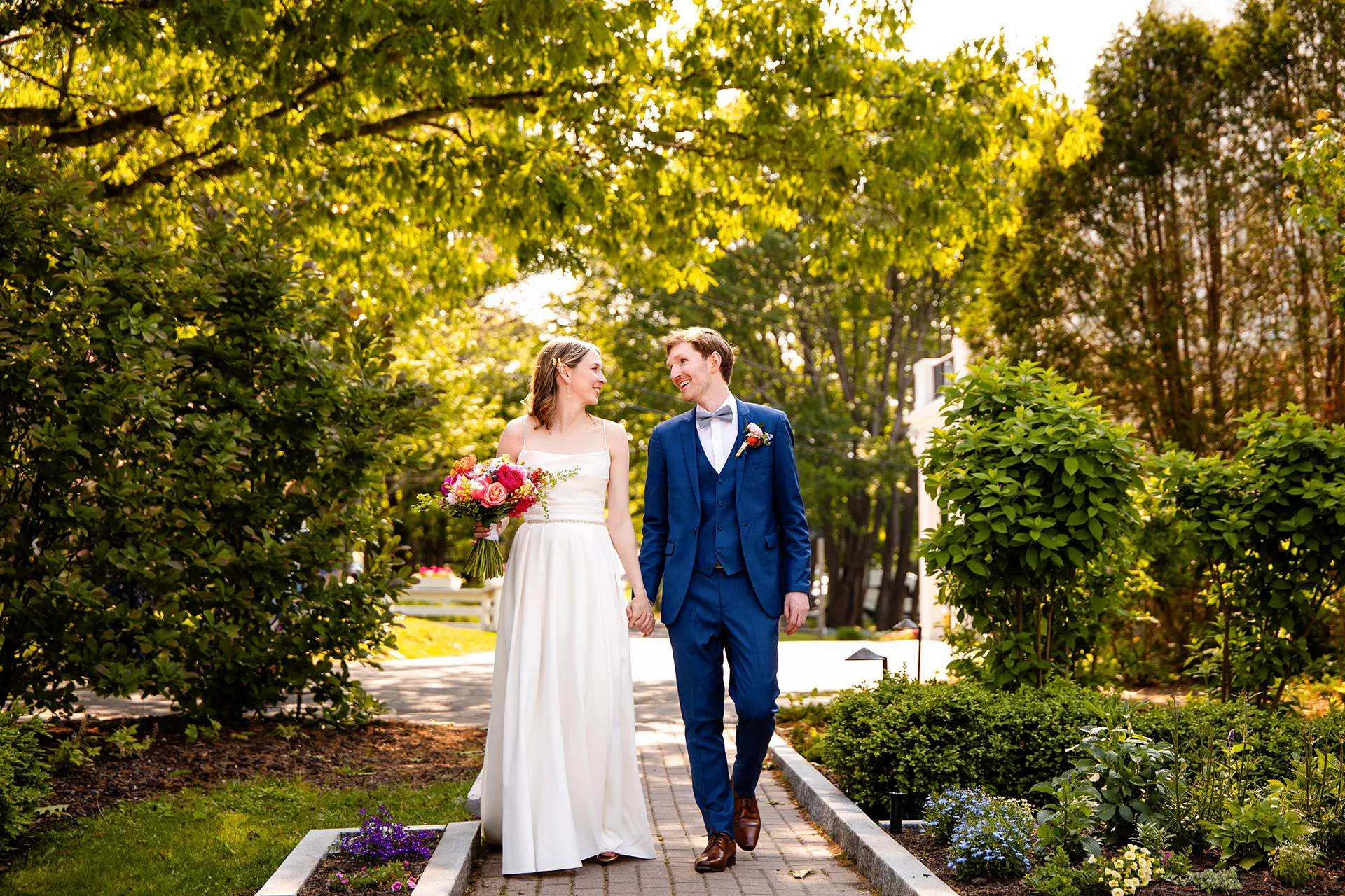 maine wedding photography caroline max 13 A newly married couple hold hands and walk during wedding portraits in a garden at the Bar Harbor Inn and Spa in Bar Harbor, Maine.