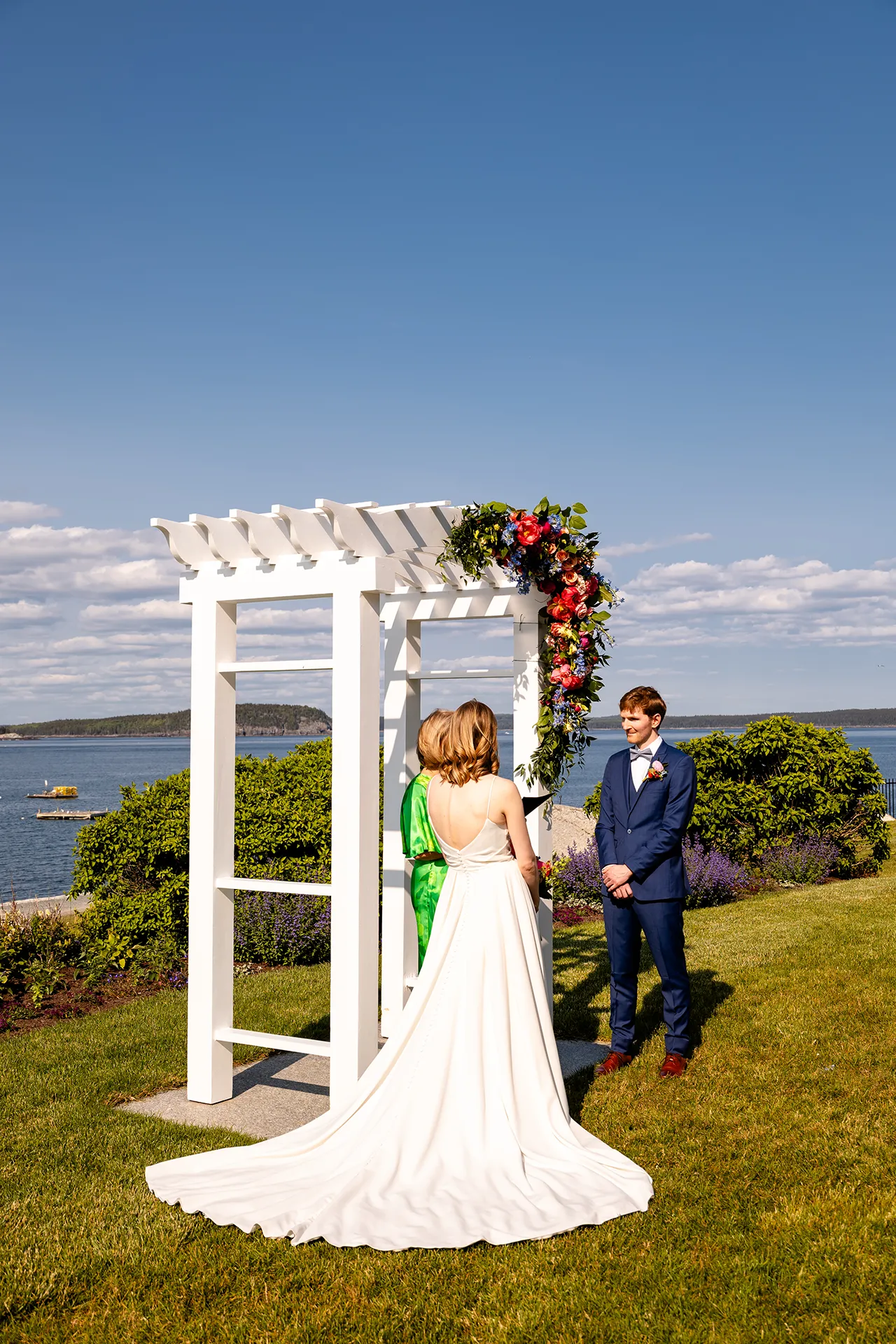 maine wedding photography caroline max 17 A bride and groom stand in front of an arbor during a wedding ceremony at the Bar Harbor Inn and Spa in Bar Harbor, Maine.