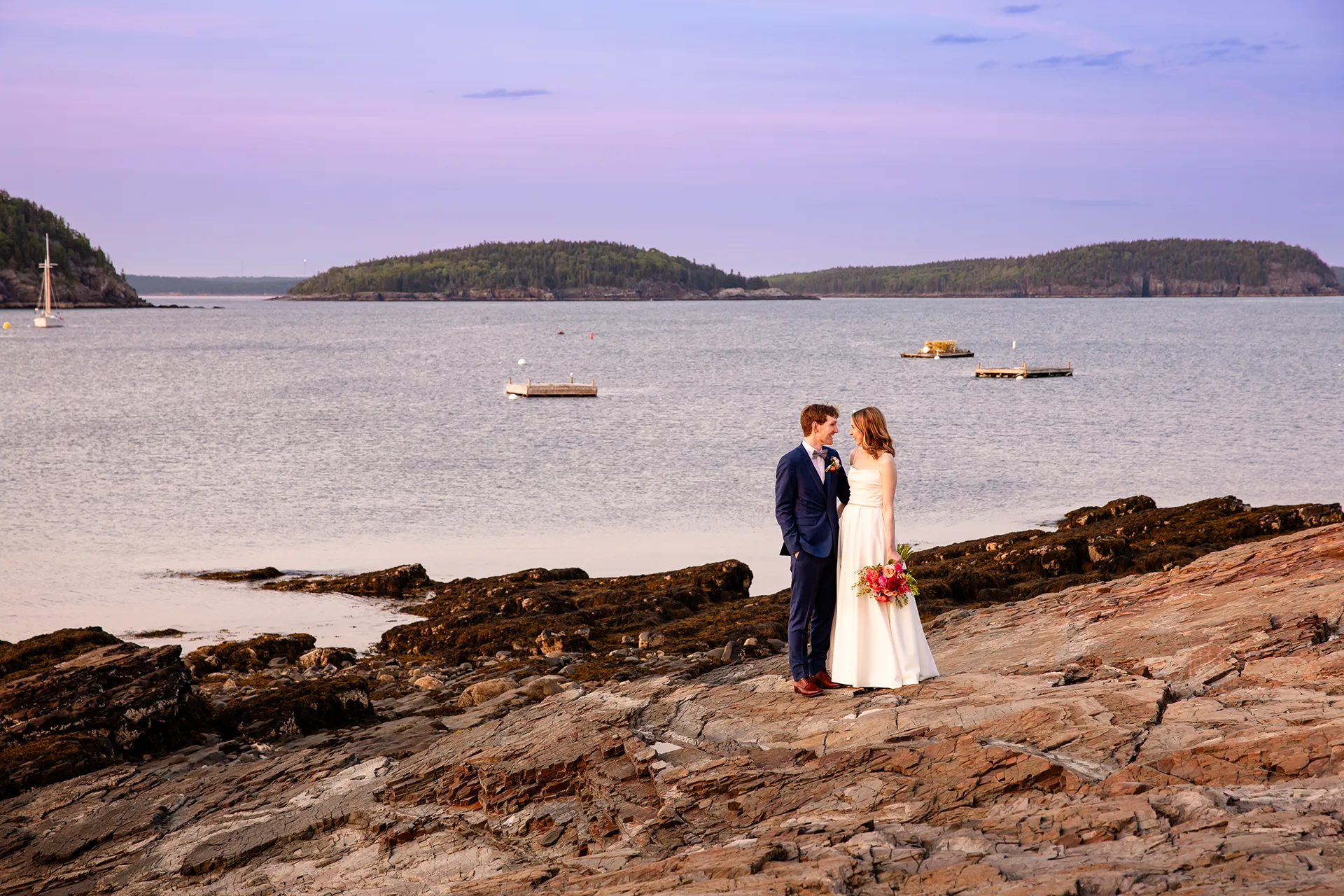 maine wedding photography caroline max 34 A bride and groom pose on rocks in front of Frenchman's Bay during wedding portraits at the Bar Harbor Inn and Spa in Bar Harbor, Maine.