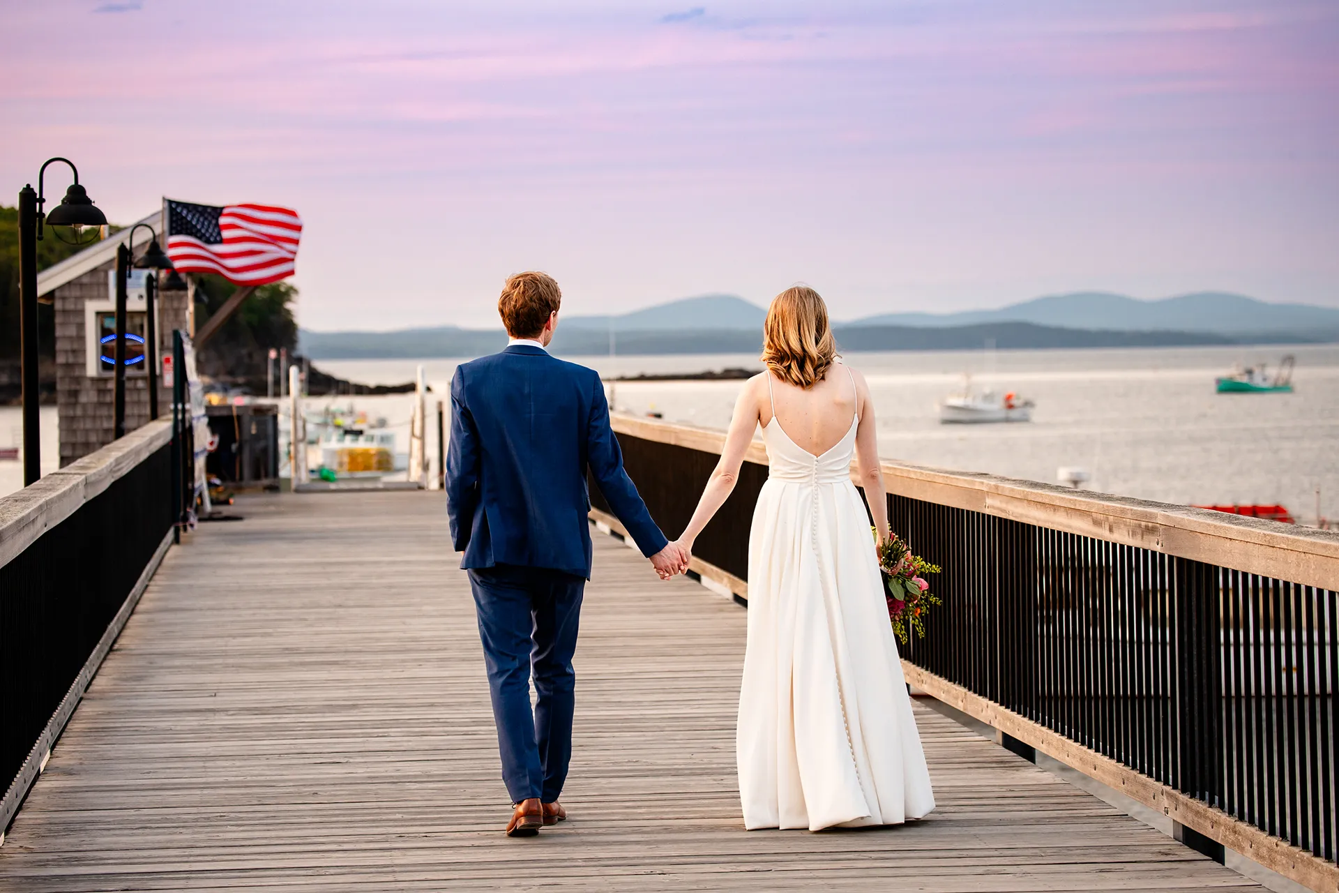 maine wedding photography caroline max 42 A bride and groom hold hands and walk along a pier during wedding portraits at the Bar Harbor Inn and Spa in Bar Harbor, Maine.