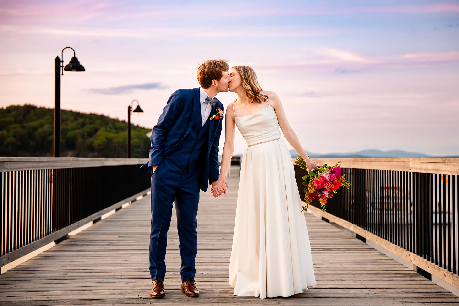 maine wedding photography caroline max 43 A newly married couple hold hands and kiss on a pier during wedding portraits at the Bar Harbor Inn and Spa in Bar Harbor, Maine.