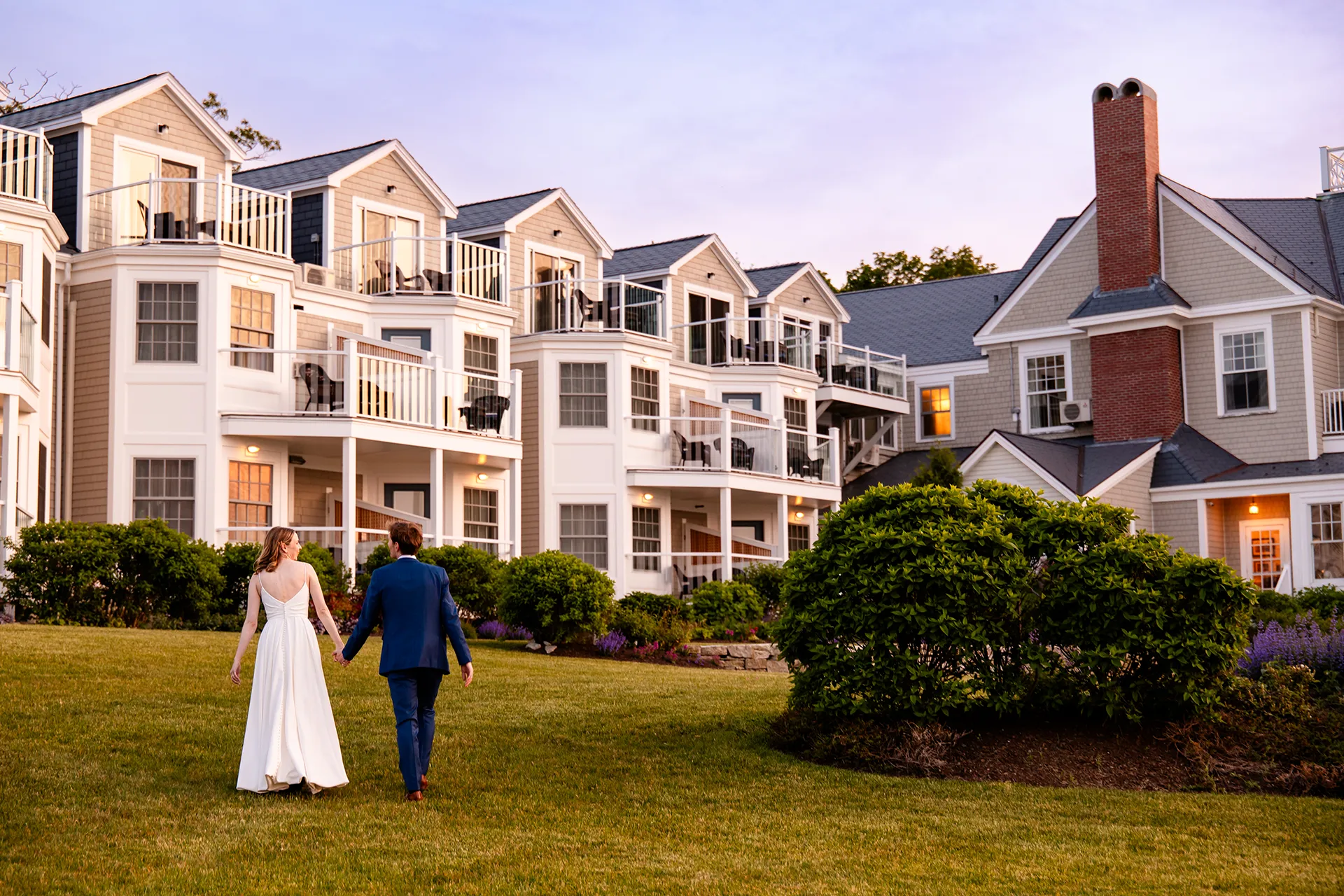 maine wedding photography caroline max 47 A bride and groom hold hands as they walk towards the Bar Harbor Inn and Spa in Bar Harbor, Maine.