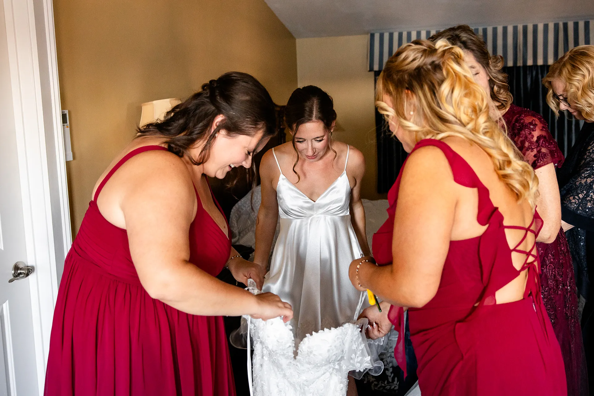 Bridesmaids help a bride into her dress as she gets ready for a wedding at the Atlantic Oceanside Hotel & Event Center in Bar Harbor, Maine.