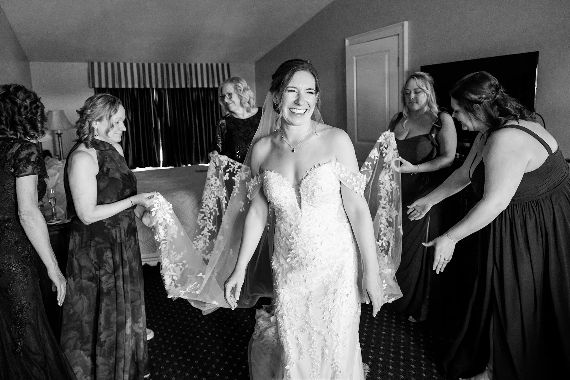 A brides laughs as bridesmaids hold her veil at the Willows on the property of the Atlantic Oceanside Hotel & Event Center in Bar Harbor, Maine.