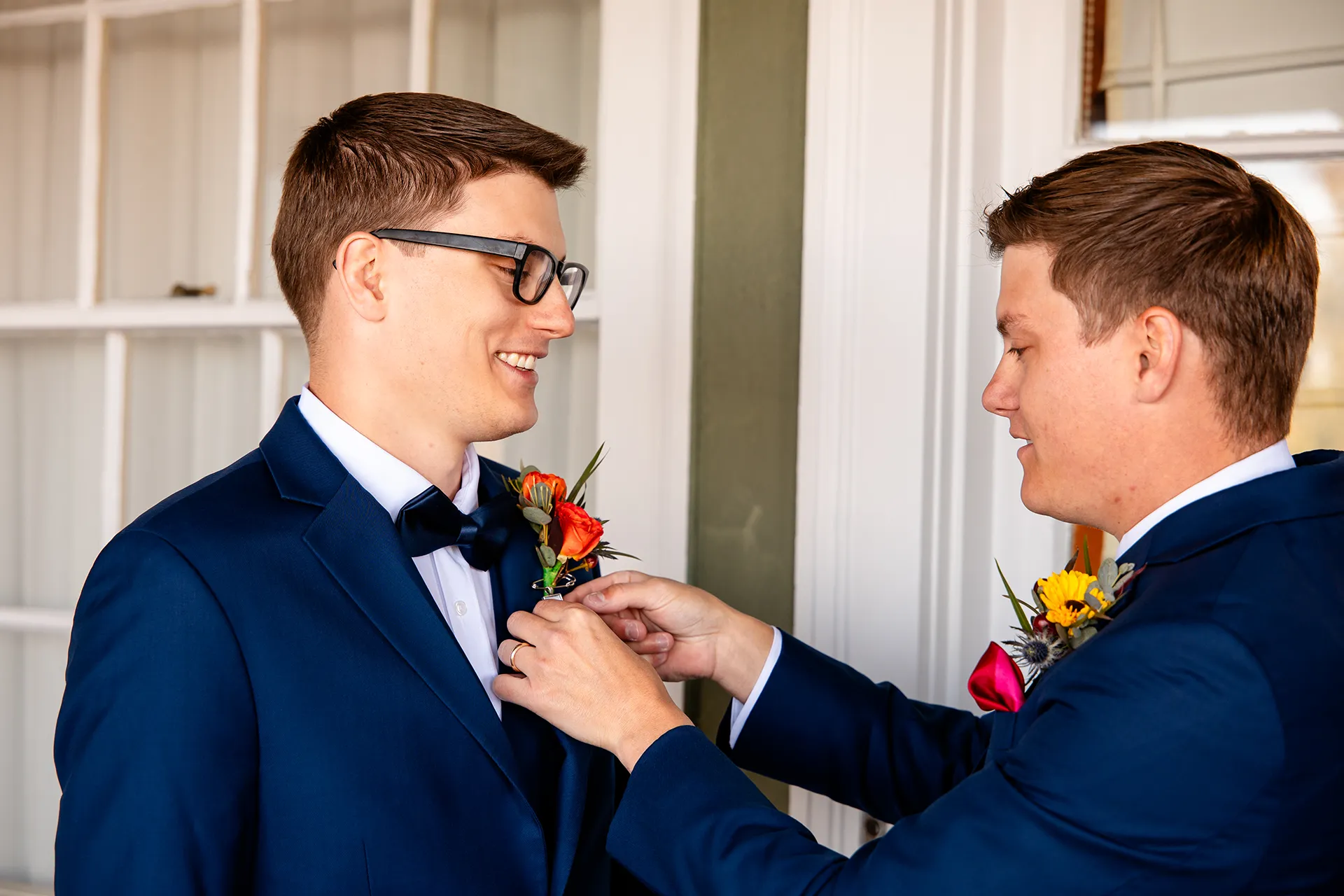 A groomsman put-ons on a groom's boutonniere as he gets ready for a wedding at the Atlantic Oceanside Hotel & Event Center in Bar Harbor, Maine.