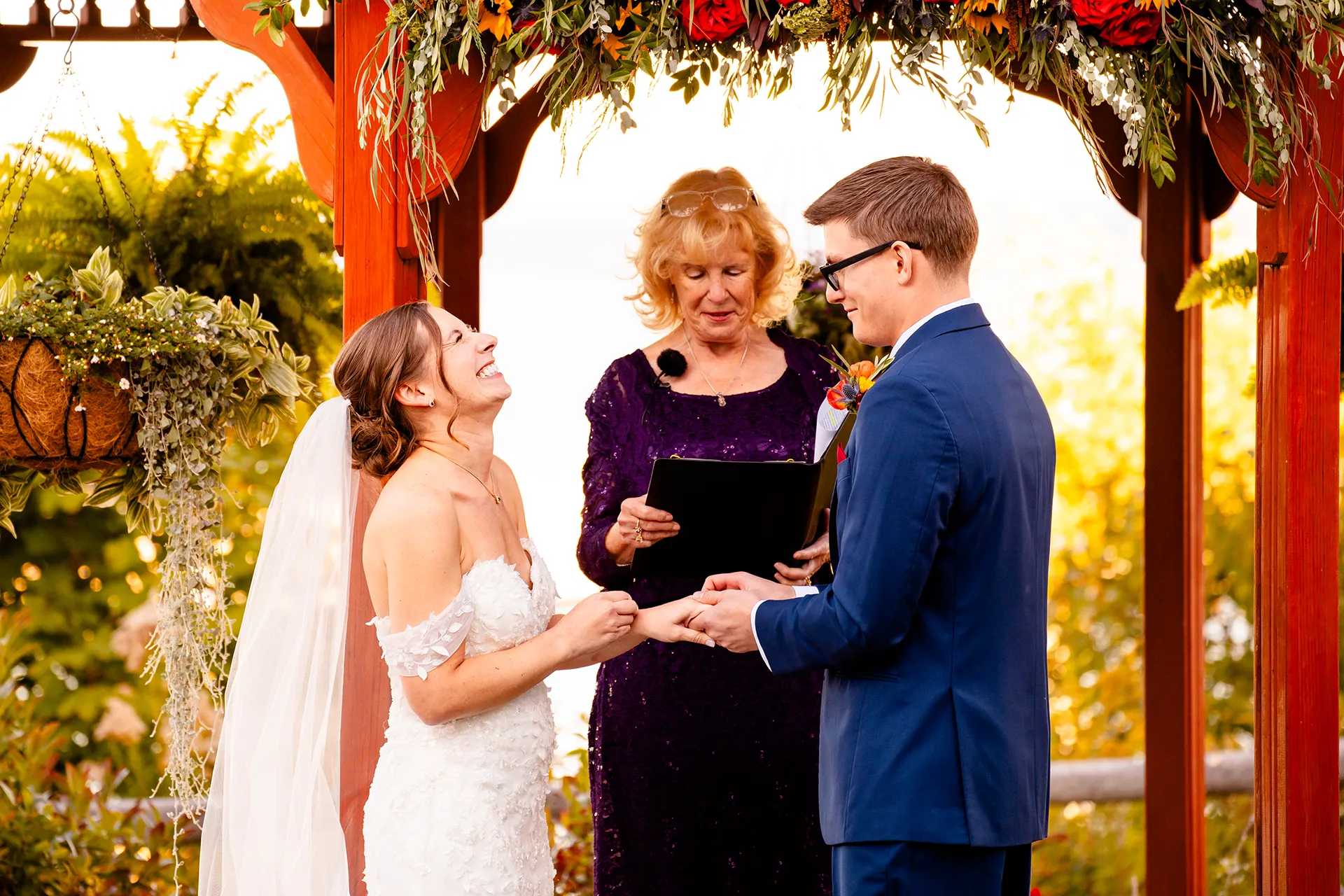 A bride laughs as a groom slides a ring on her finger during a wedding ceremony at the Atlantic Oceanside Hotel & Event Center in Bar Harbor, Maine.