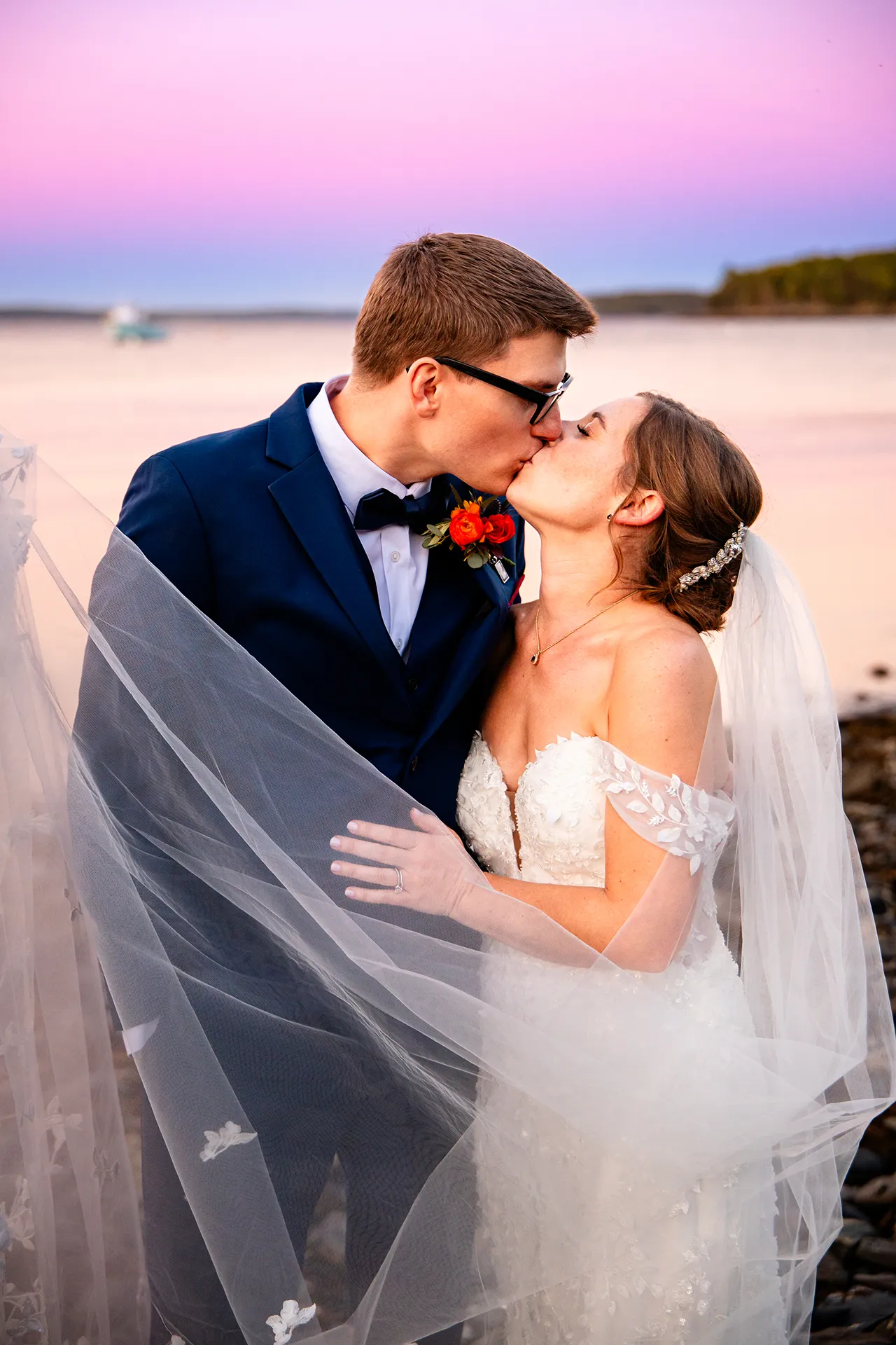 A newly married couple kiss during sunset wedding portraits on a beach at the Atlantic Oceanside Hotel & Event Center in Bar Harbor, Maine.