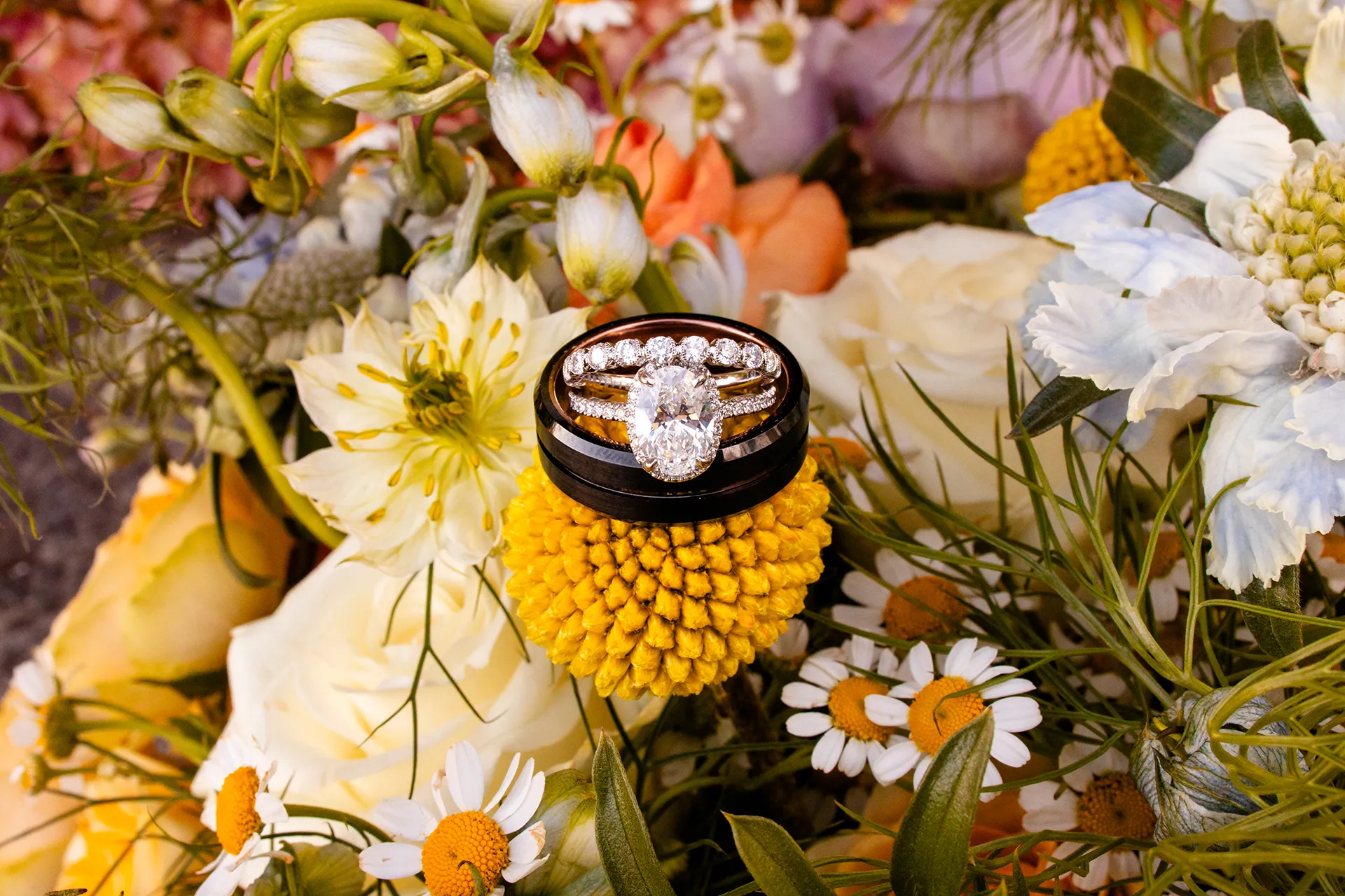 A closeup of a diamond engagement and wedding ring sitting on top of black groom's band at the Bar Harbor Inn and Spa in Maine.