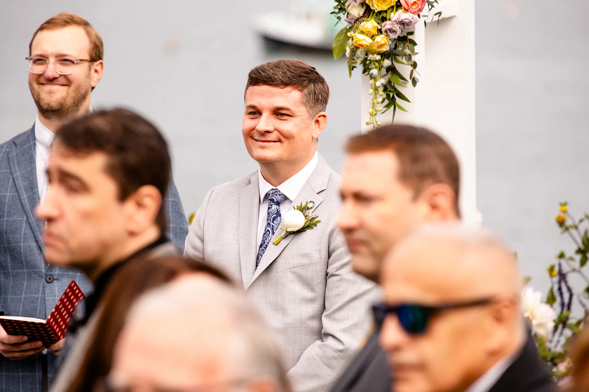A groom smiles as he watches a bride walk down the aisle during a wedding ceremony at the Bar Harbor Inn and Spa near Acadia National Park in Maine.