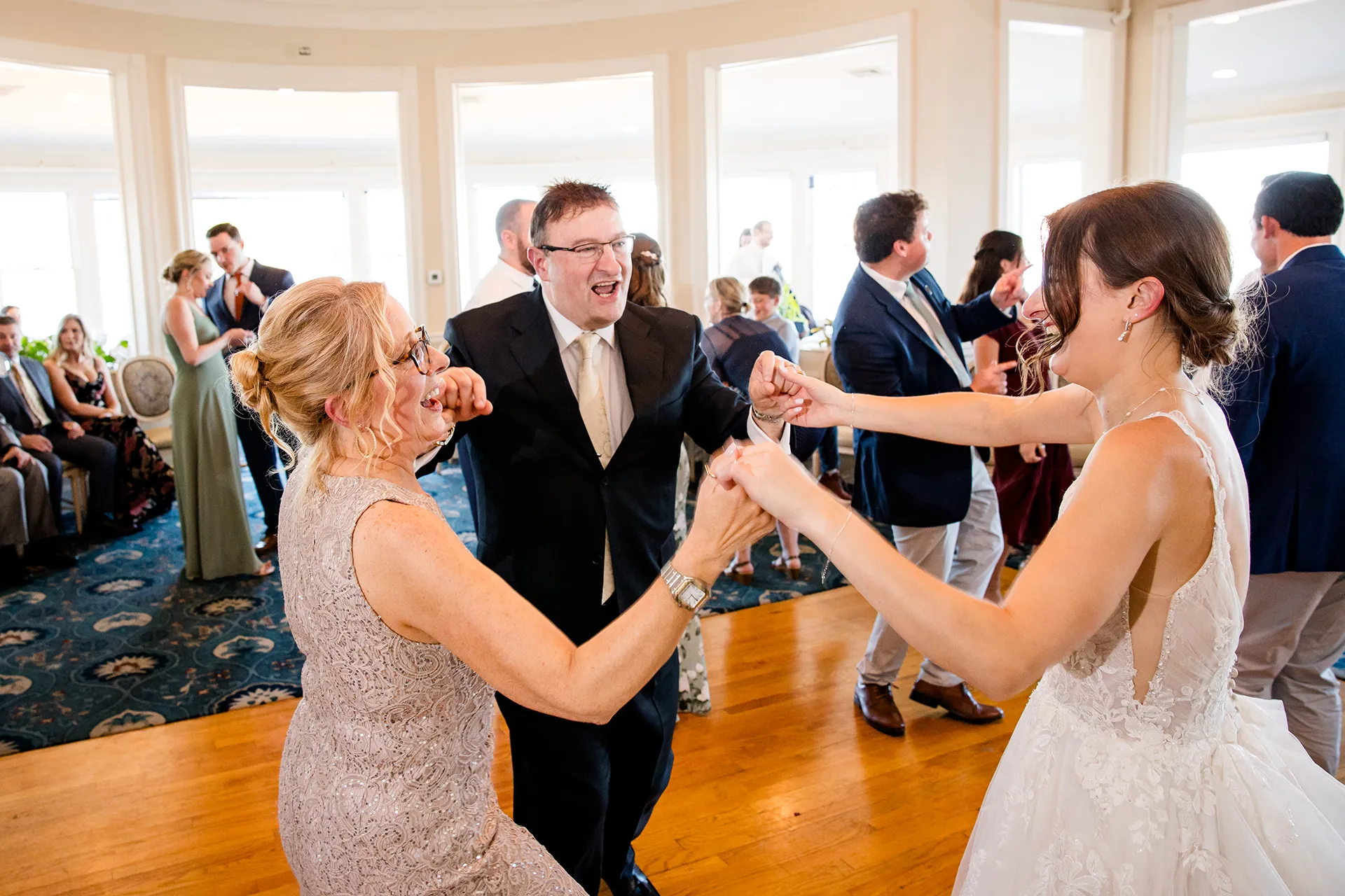 A bride and her parents laugh as they dance during a wedding reception at the Bar Harbor Inn and Spa near Acadia National Park in Maine.