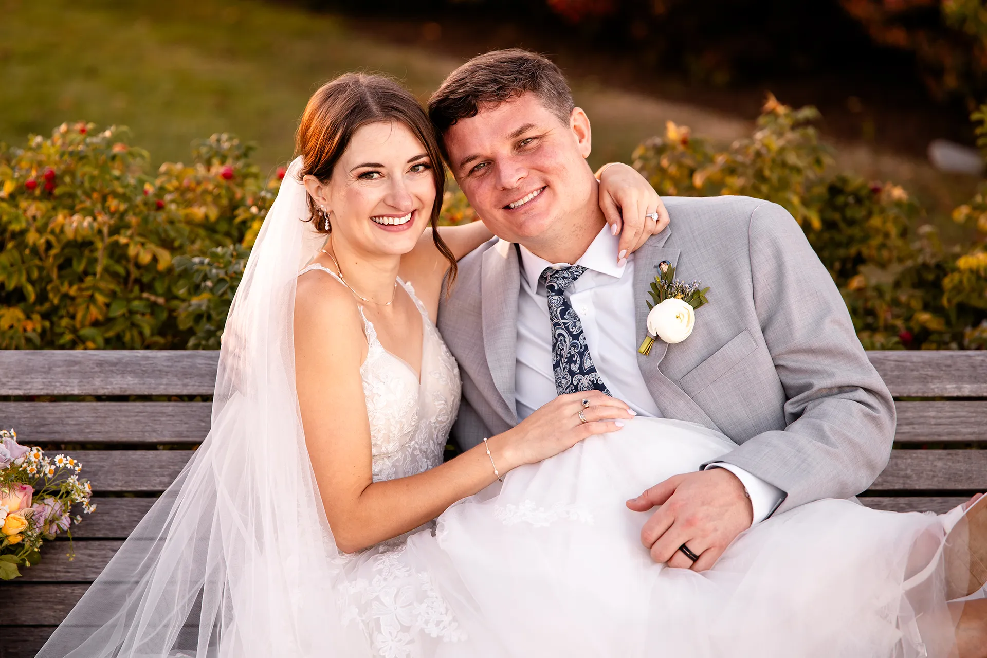 A bride and groom pose on a bench during wedding portraits on the property of the Bar Harbor Inn near the Acadia National Park in Maine.