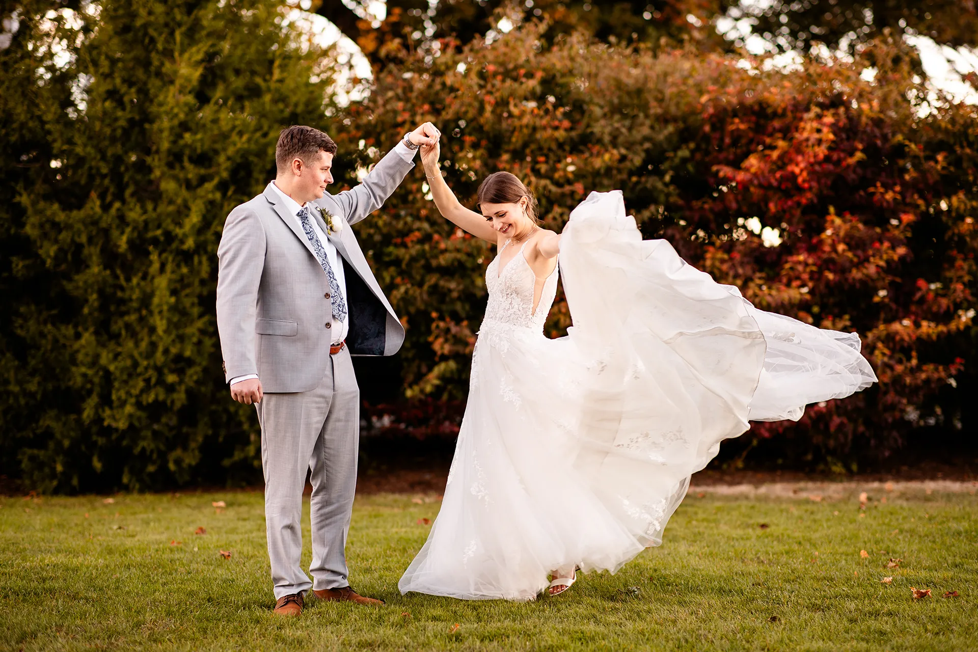 A groom holds a brides hand as she spins during wedding portraits on the property of the Bar Harbor Inn near the Acadia National Park in Maine.