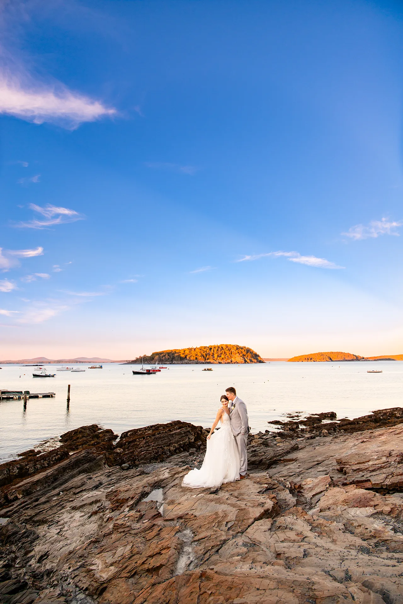 A groom kisses a bride on the head while they stand on a cliff overlooking Frenchmans Bay at the Bar Harbor Inn and Spa near the Acadia National Park.