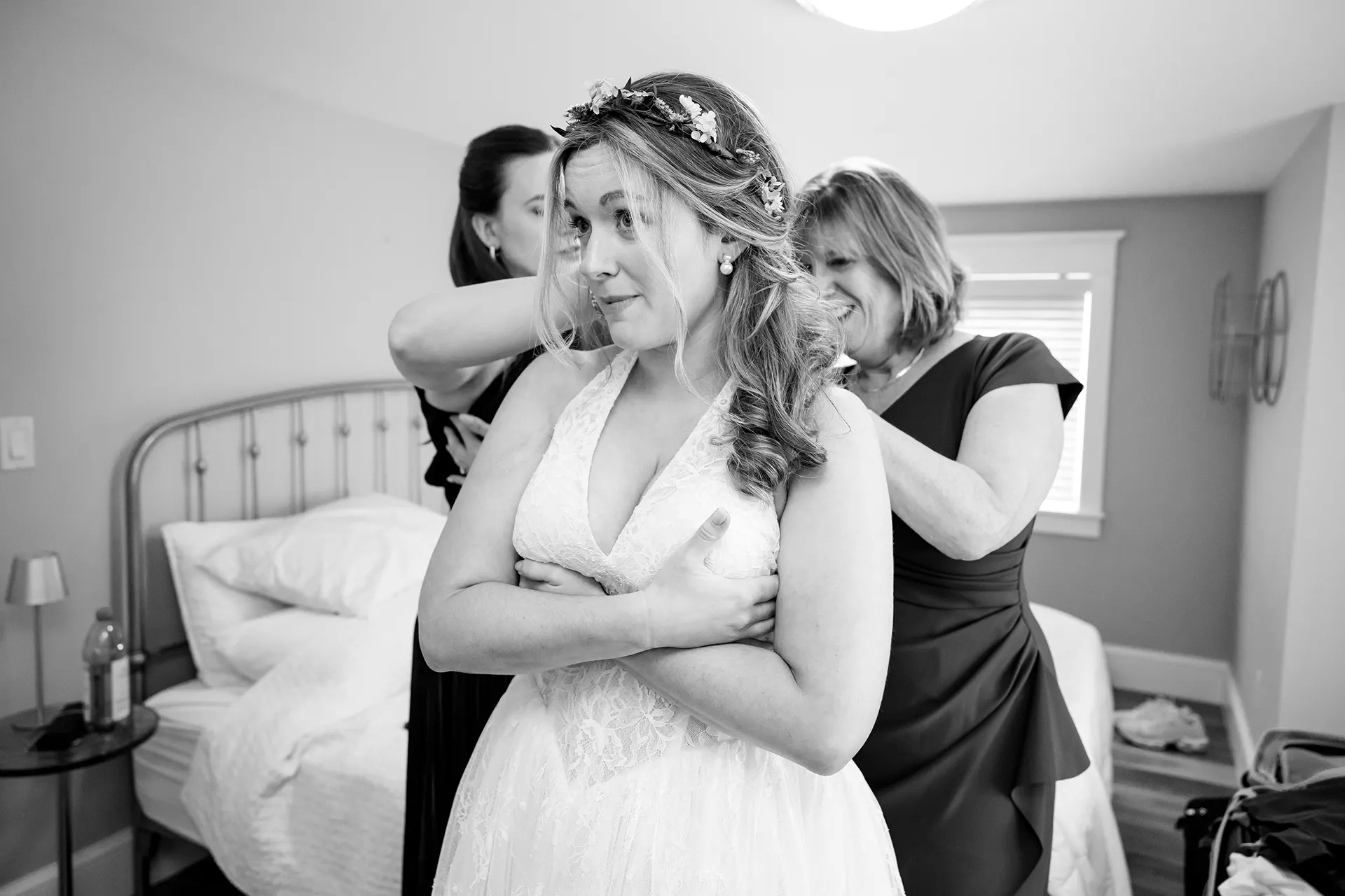 A bride is helped into her wedding dress by her mom and sister as she gets ready for her wedding in Bangor, Maine.