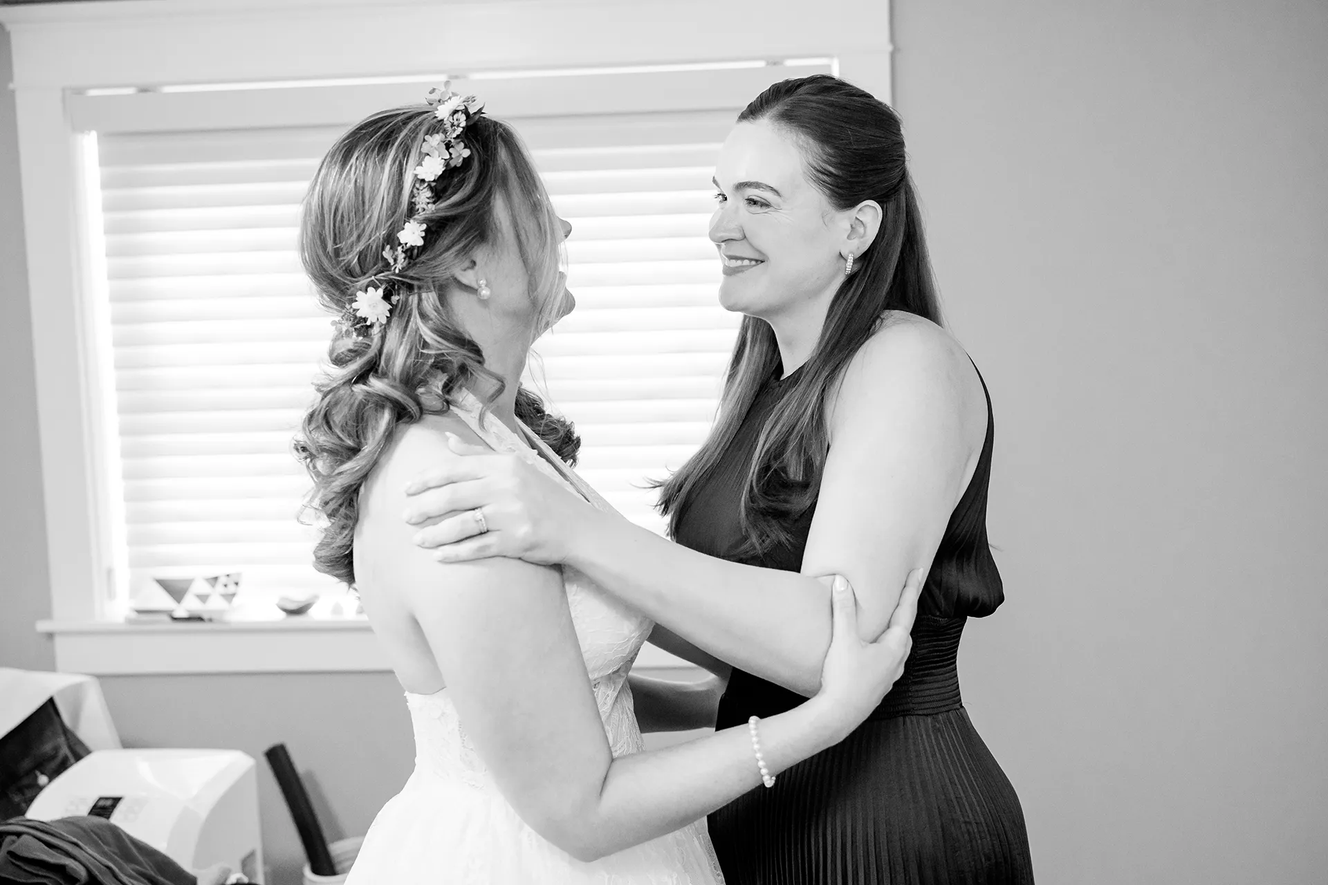 A woman smiles and hugs a bride as she gets ready for her wedding in Bangor, Maine.