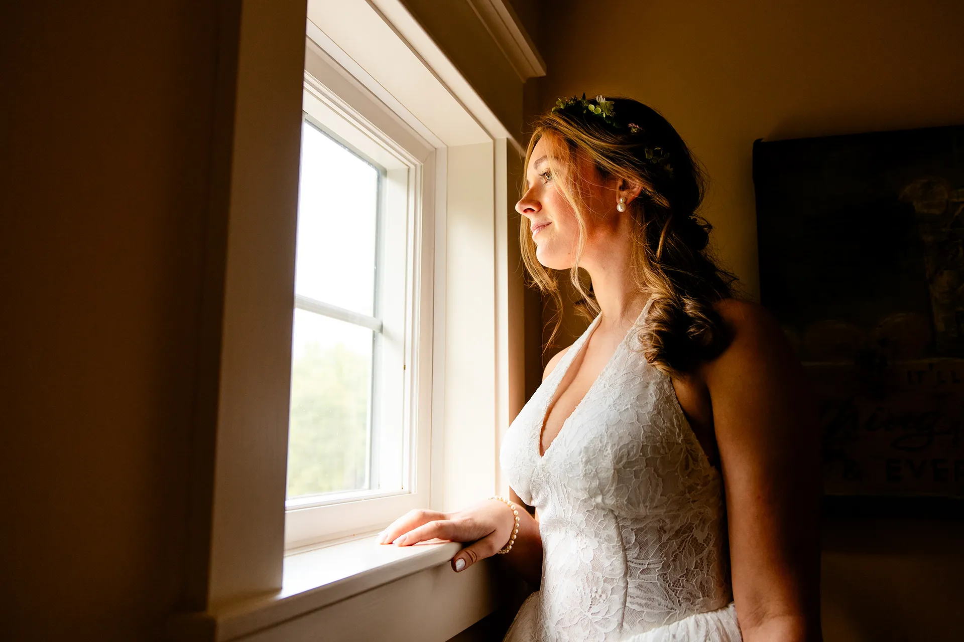 A bride looks out a window during bridal portraits at a private residence in Bangor, Maine.