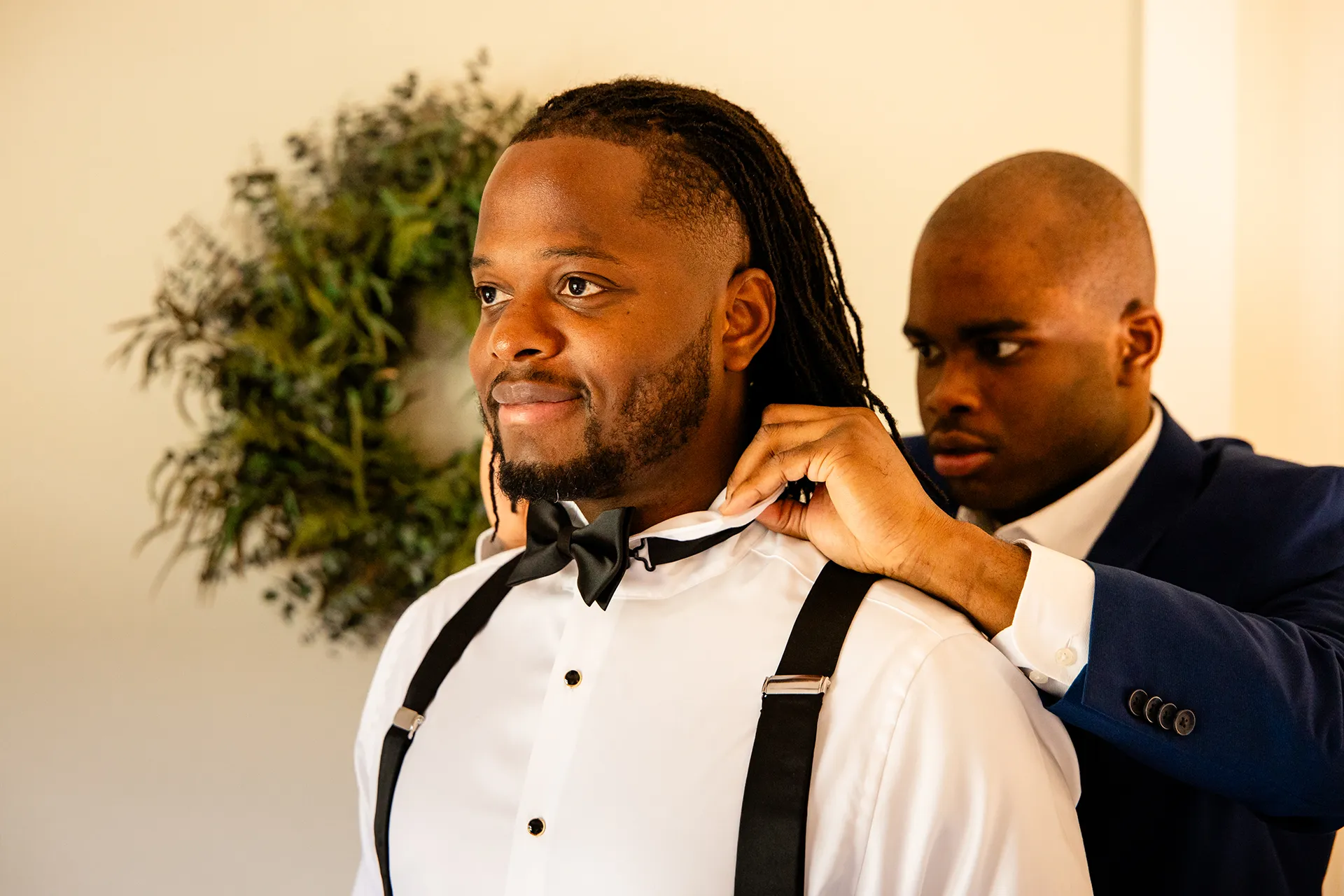 A man helps a groom put on his bowtie as he gets ready for a wedding in Bangor, Maine.