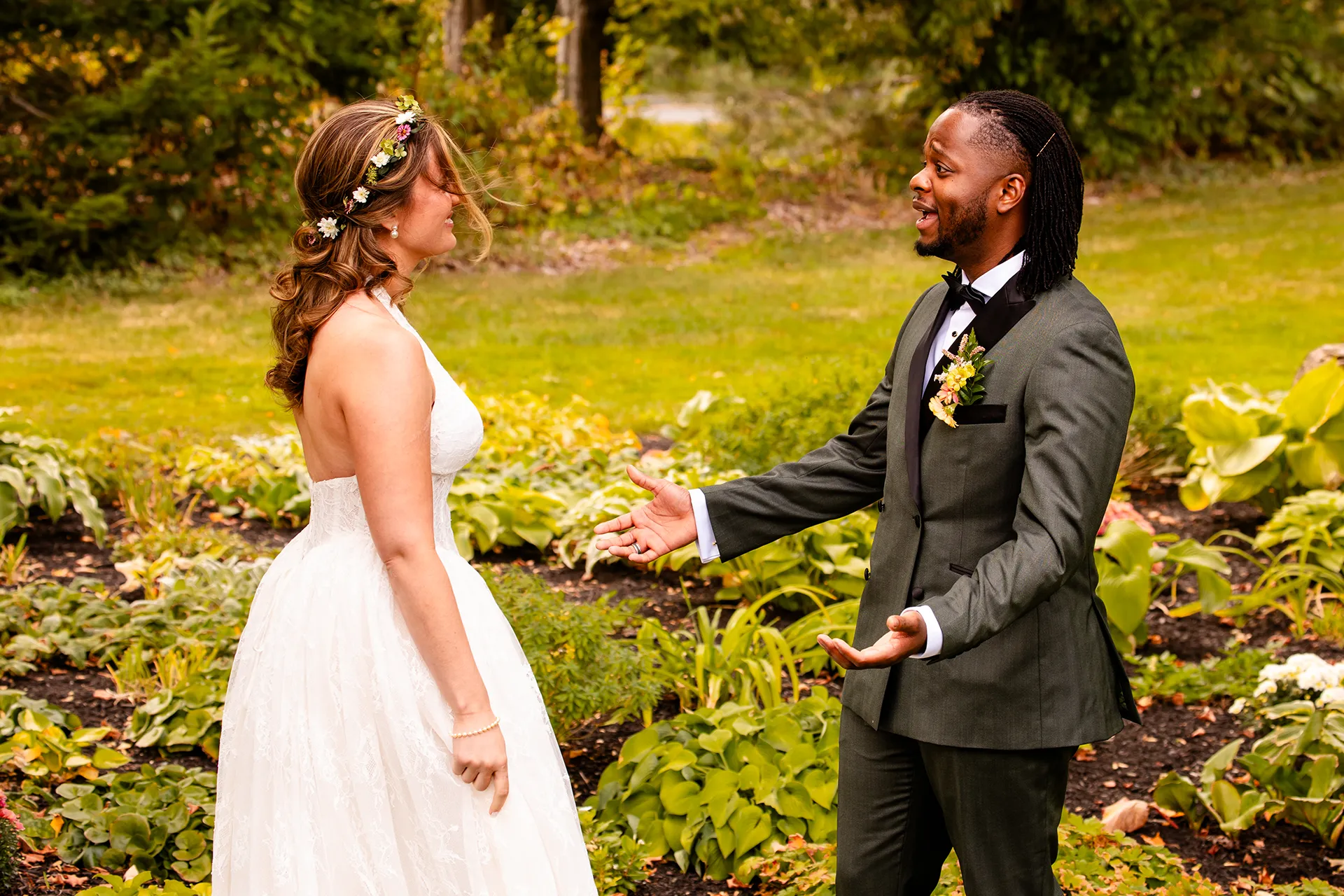 A groom laughs as he sees a bride for the first time during a first look in a garden in Bangor, Maine.