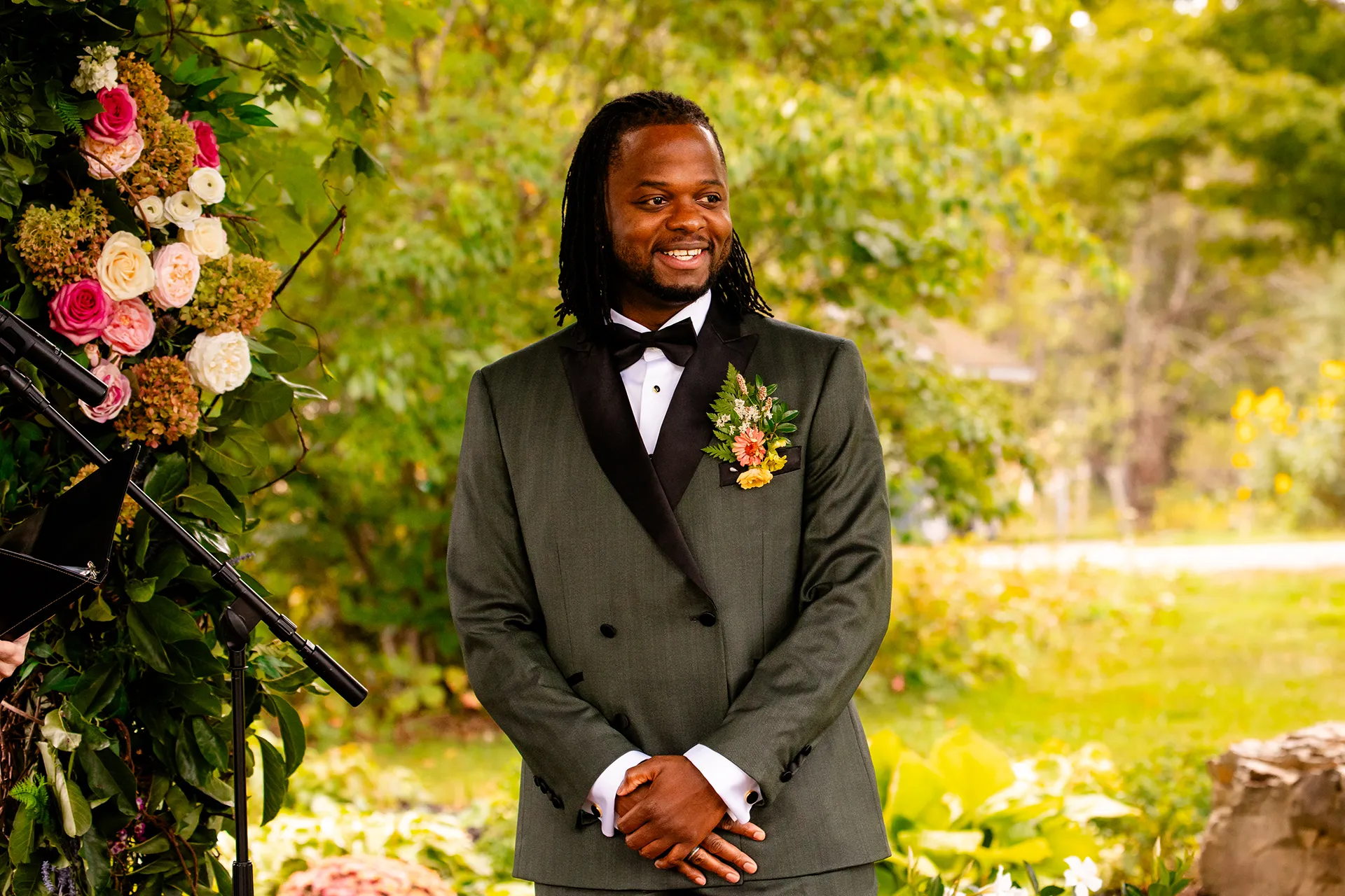 A groom smiles as he watches a bride walk down the aisle during a wedding ceremony in Bangor, Maine.