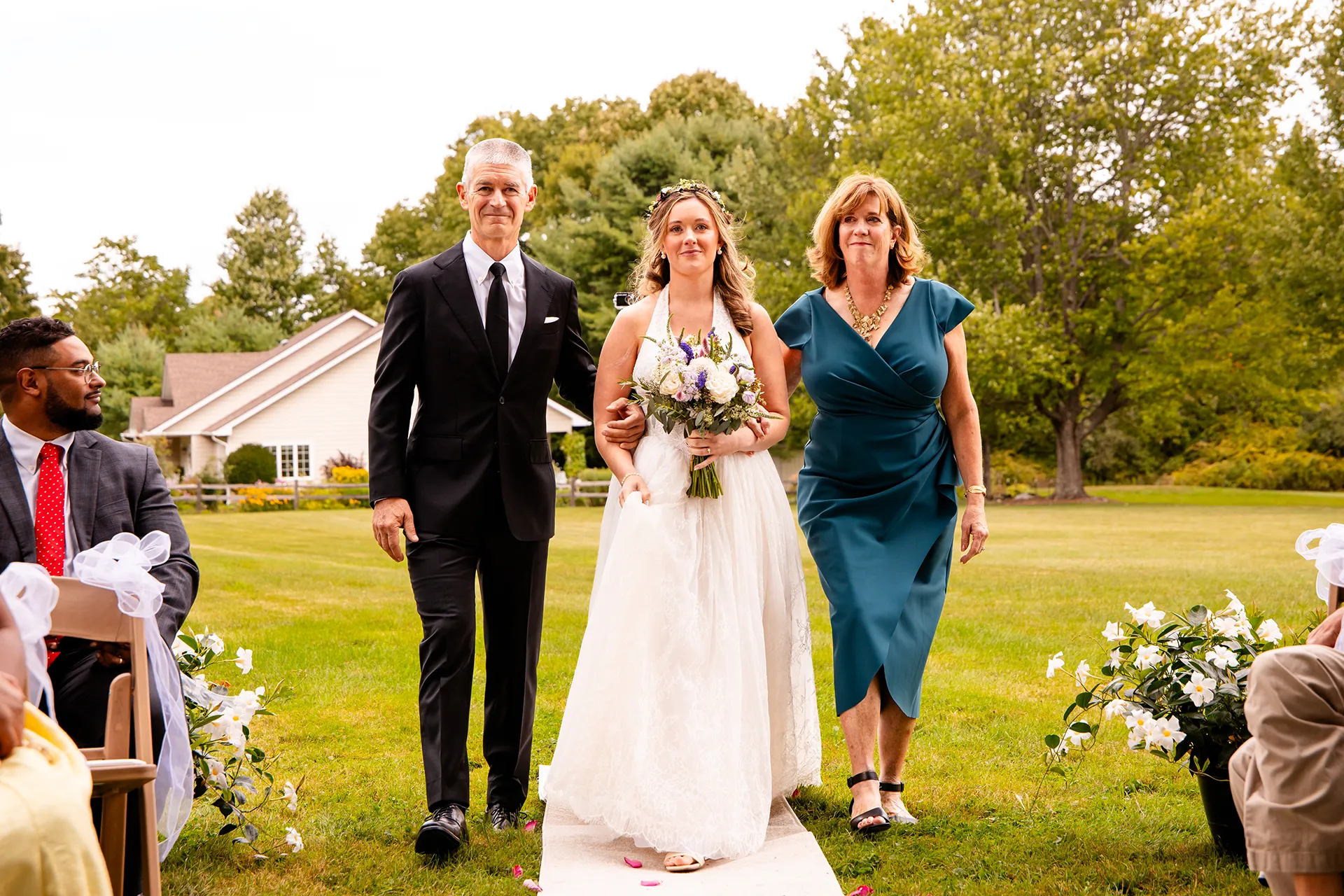 A bride and her parents smile as they walk down the aisle during a wedding ceremony in Bangor, Maine.