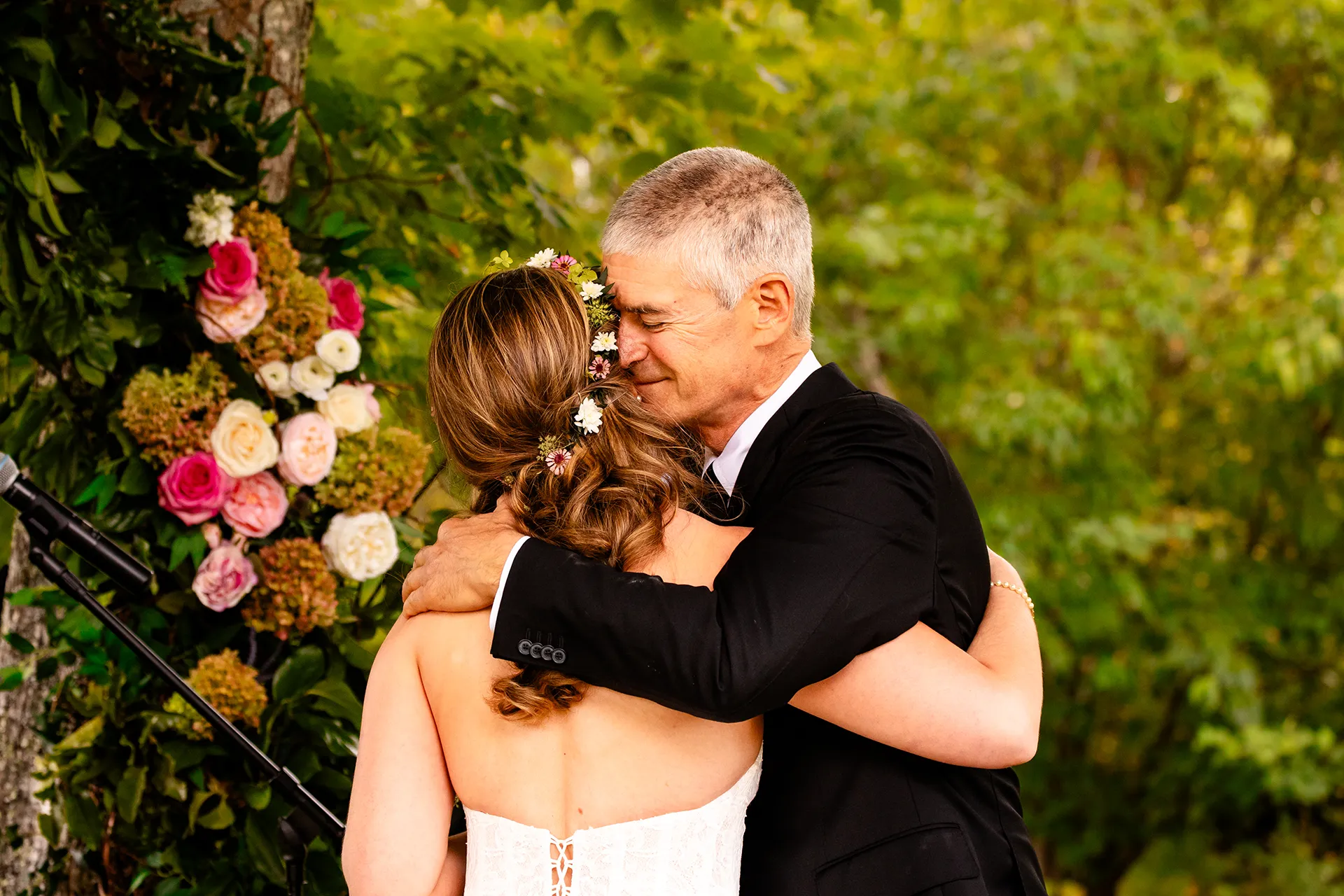 A dad smiles as he hugs a bride during a wedding ceremony in Bangor, Maine.