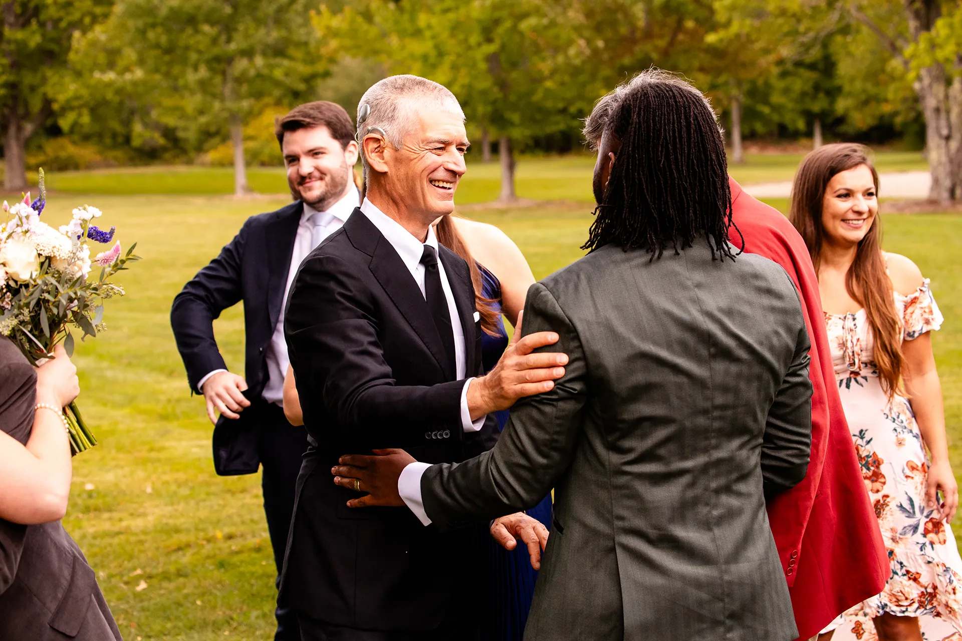 A man smiles as he claps a groom on the back after a wedding ceremony in Bangor, Maine.