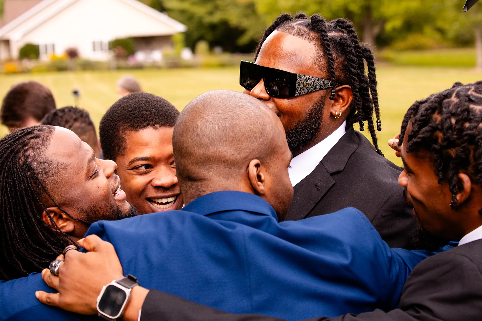 A groom is hugged by a bunch of laughing guys after a wedding ceremony in Bangor, Maine.