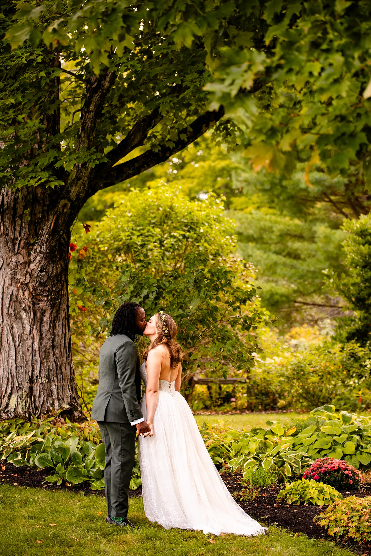 A bride and groom kiss in a garden during wedding portraits in Bangor, Maine.