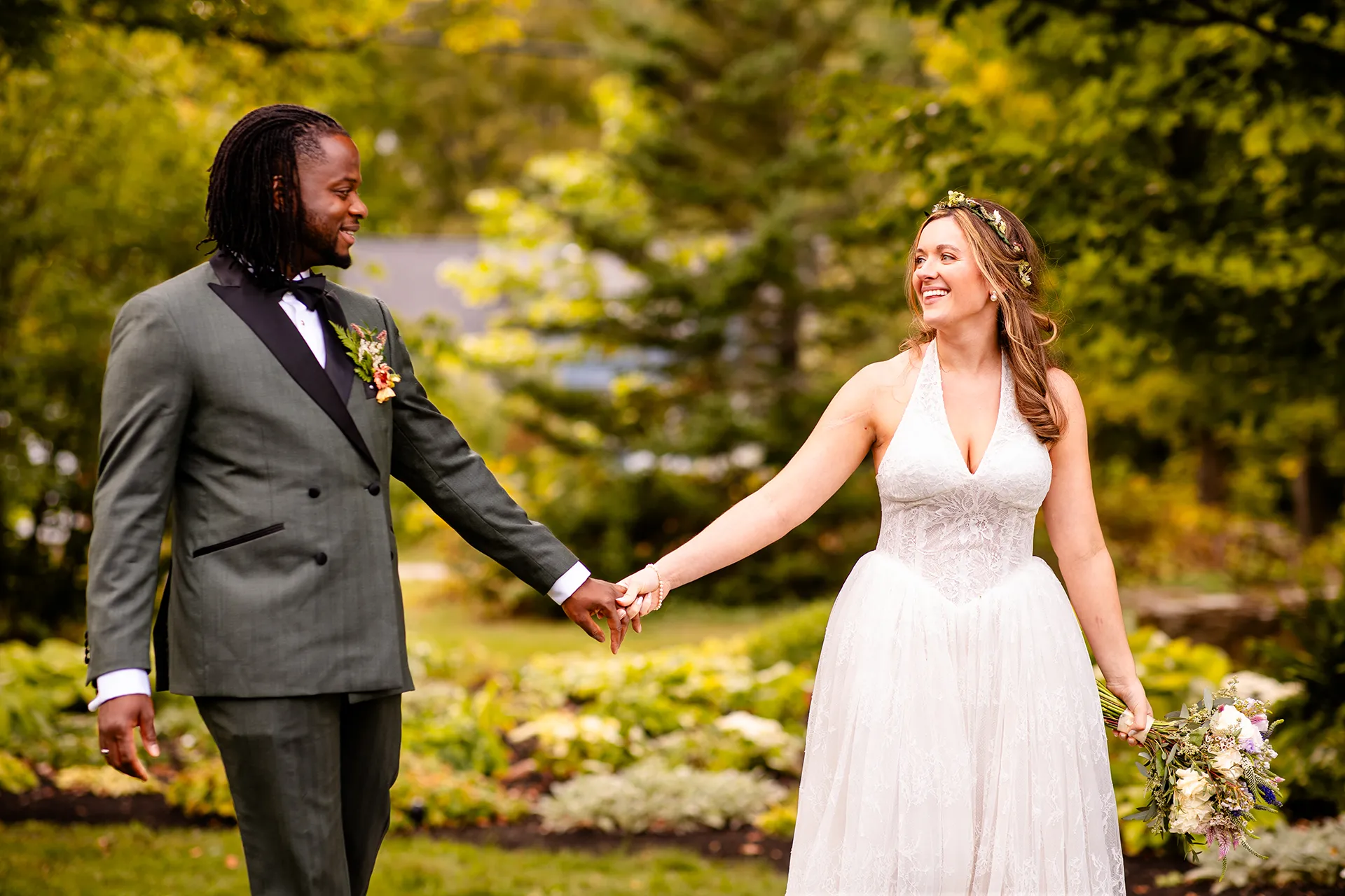 A bride and groom hold hands as they laugh during wedding portraits in Bangor, Maine.
