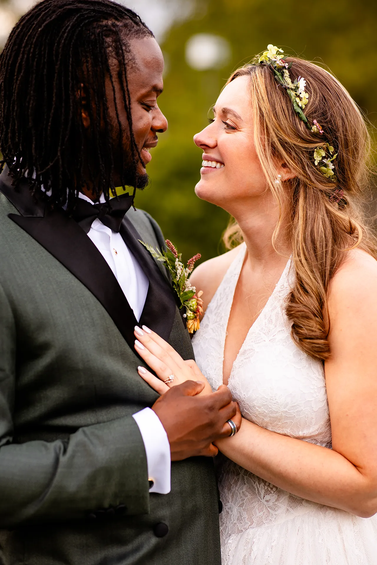 A bride and groom smile at each other while they hold hands during wedding portraits in Bangor, Maine.