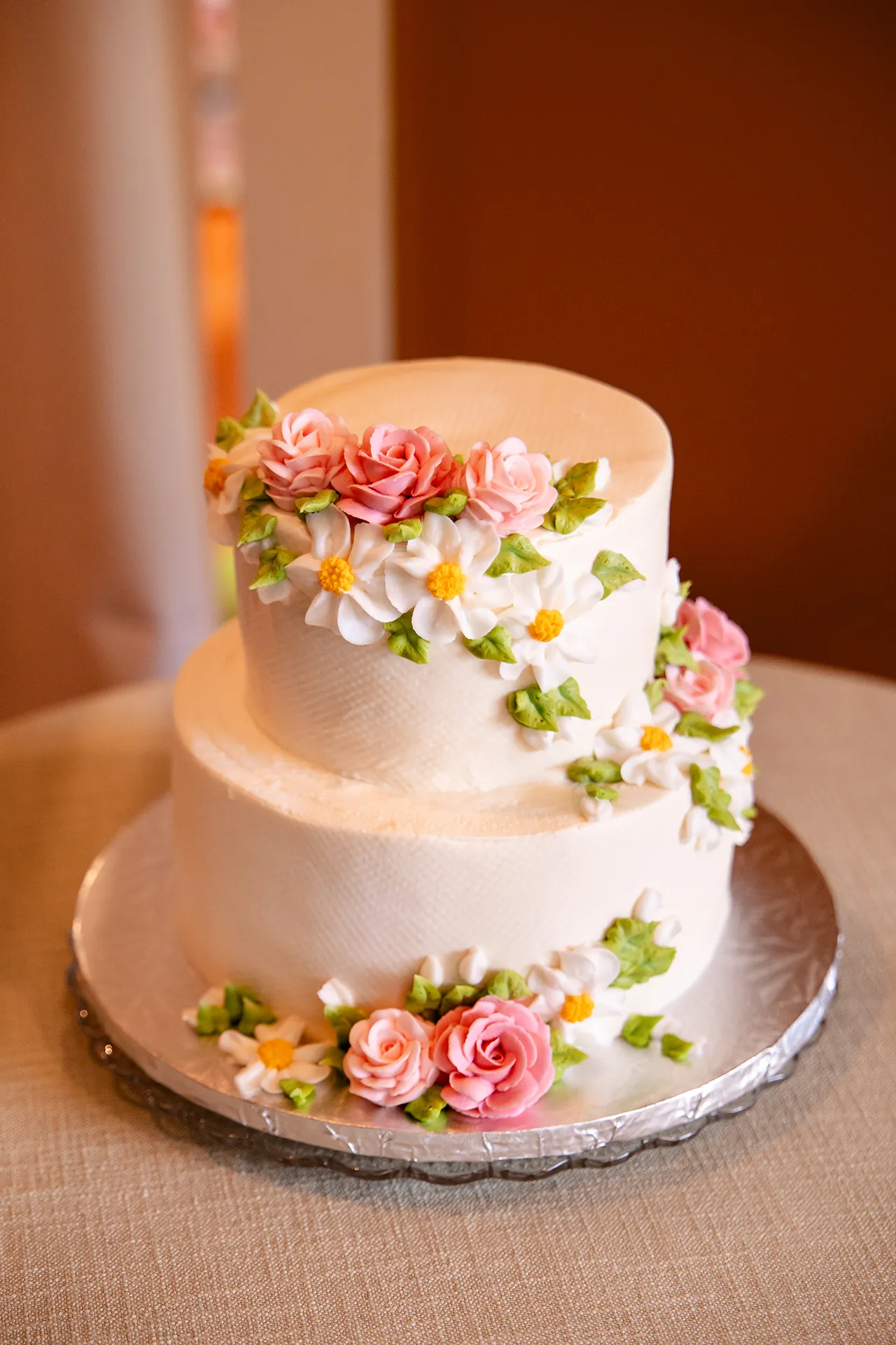 A closeup of a white wedding cake with pink and white flowers for a wedding reception in Bangor, Maine.
