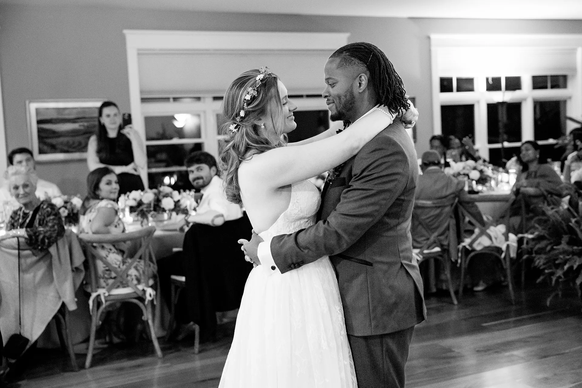 A bride and groom share a first dance in front of their guests during a micro wedding reception at a private residence in Bangor, Maine.