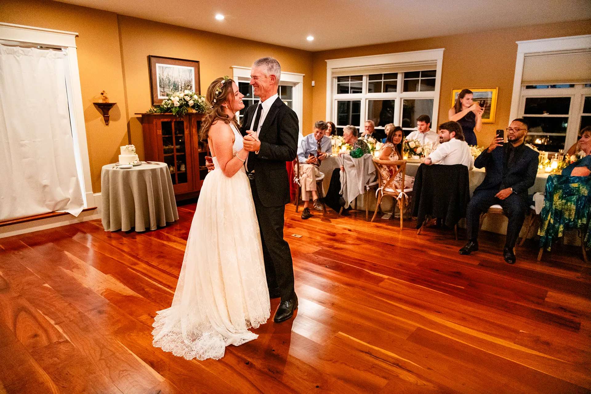 A bride and her dad laugh as they dance during a micro wedding reception at a private residence in Bangor, Maine.